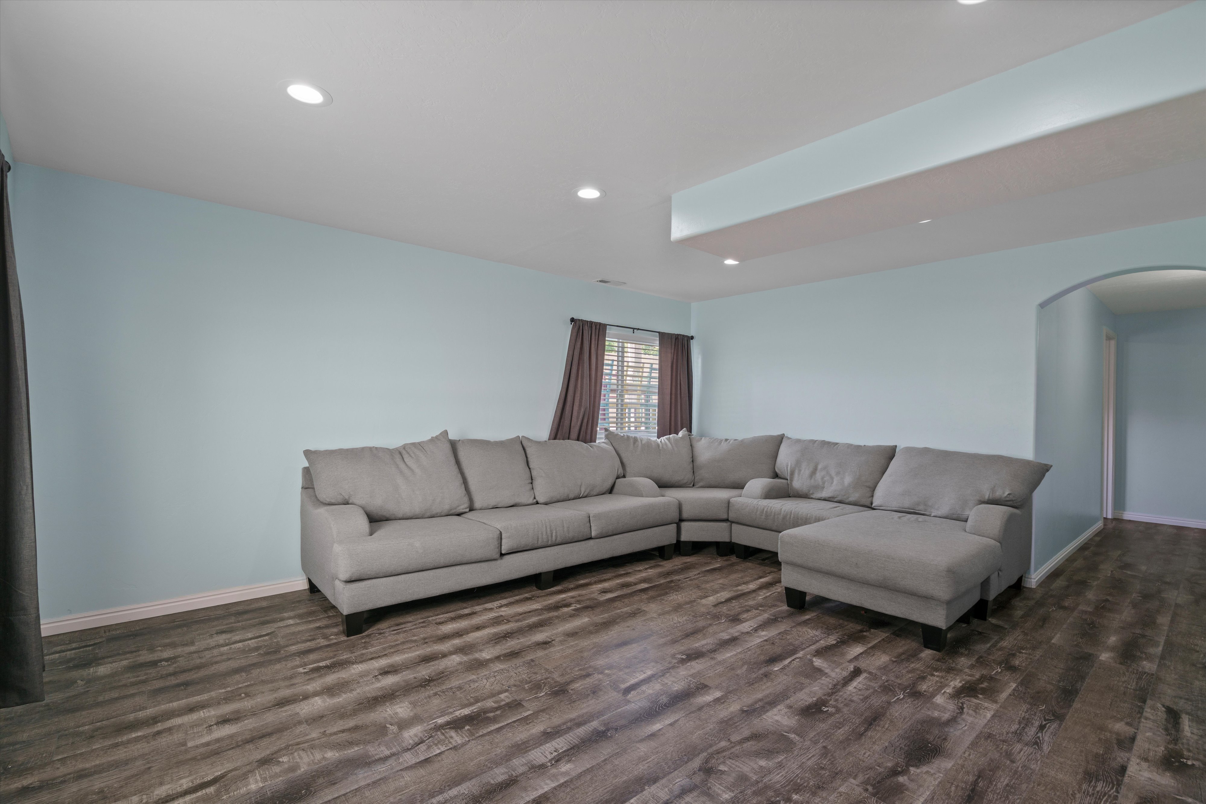 Spacious room featuring wood-finish flooring, recessed lighting, and a soffit with integrated lighting