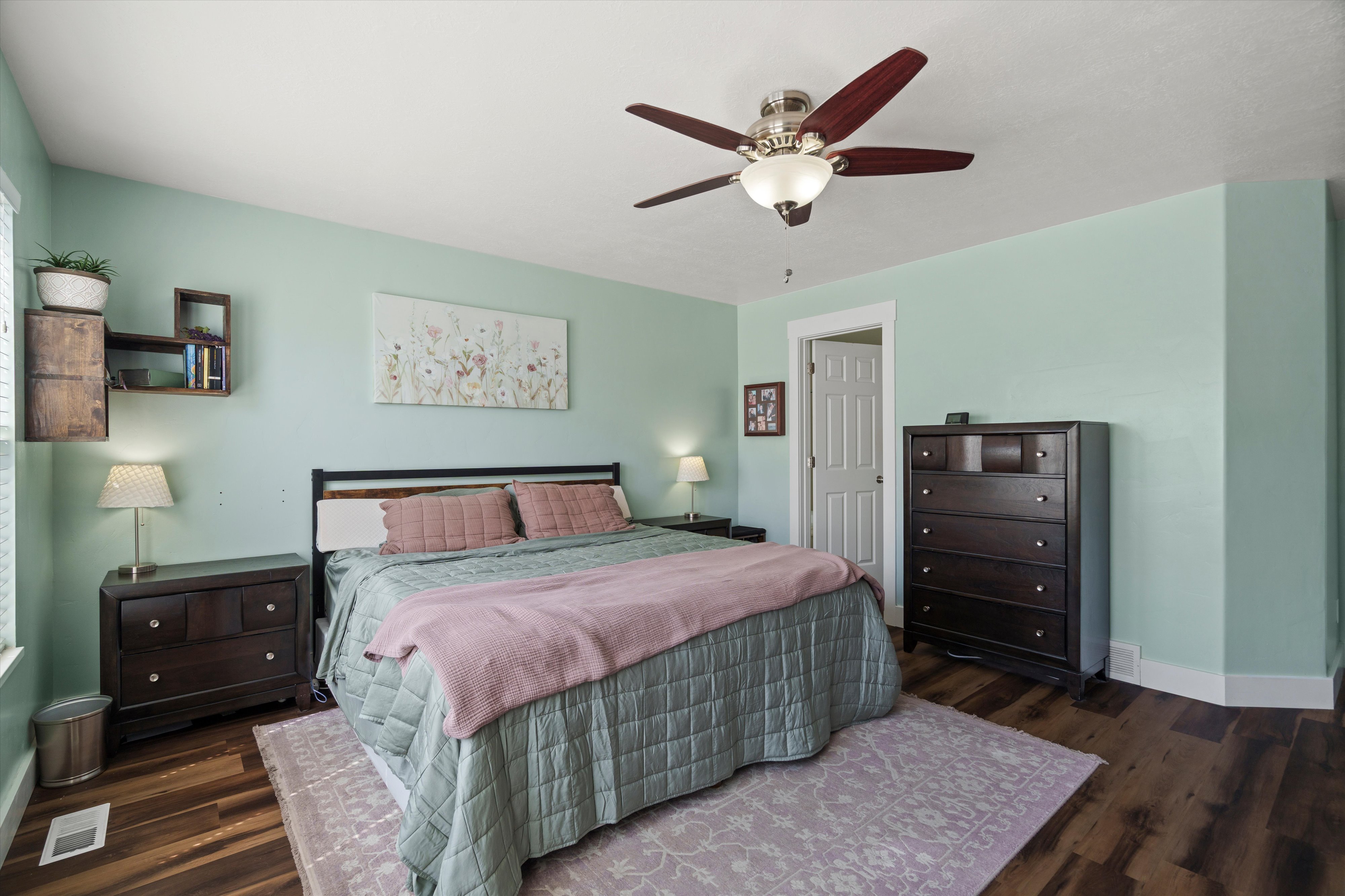 Spacious room featuring wood-finish flooring, a ceiling fan with integrated lighting, and light-colored walls