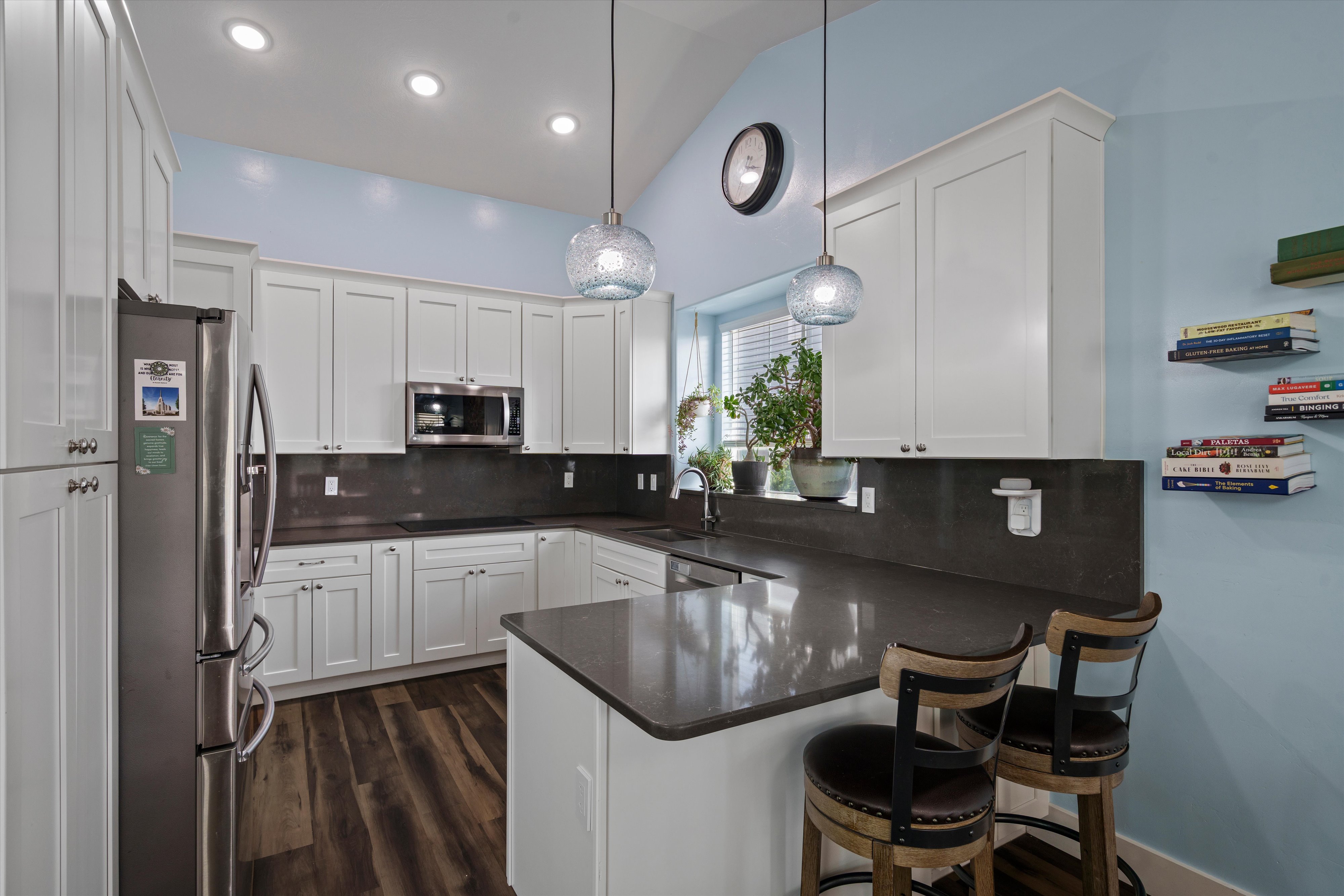 Kitchen featuring white cabinetry, dark countertops, stainless steel appliances, wood-finish flooring, and recessed lighting