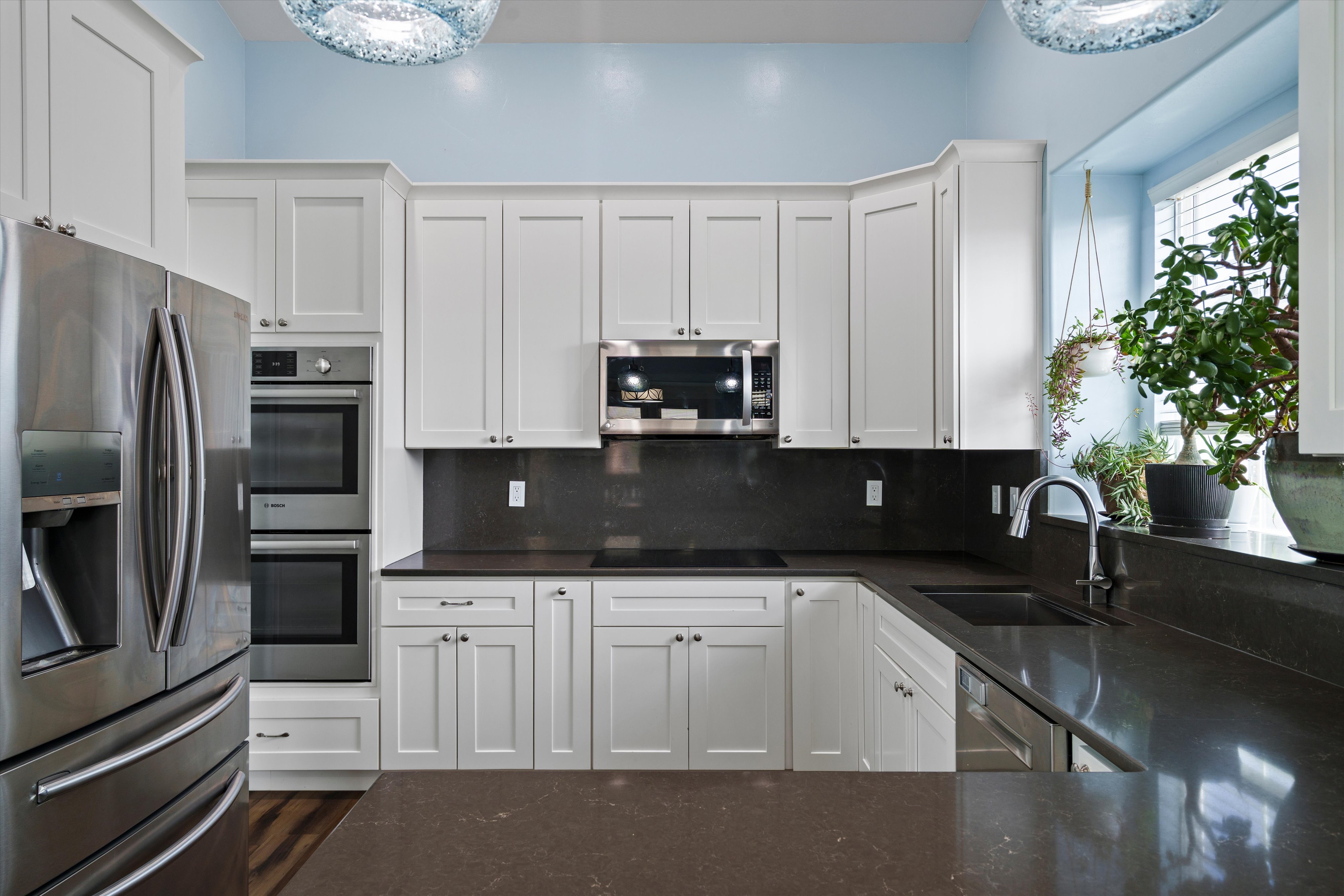 Kitchen featuring white shaker cabinetry, dark countertops, and a built-in double oven