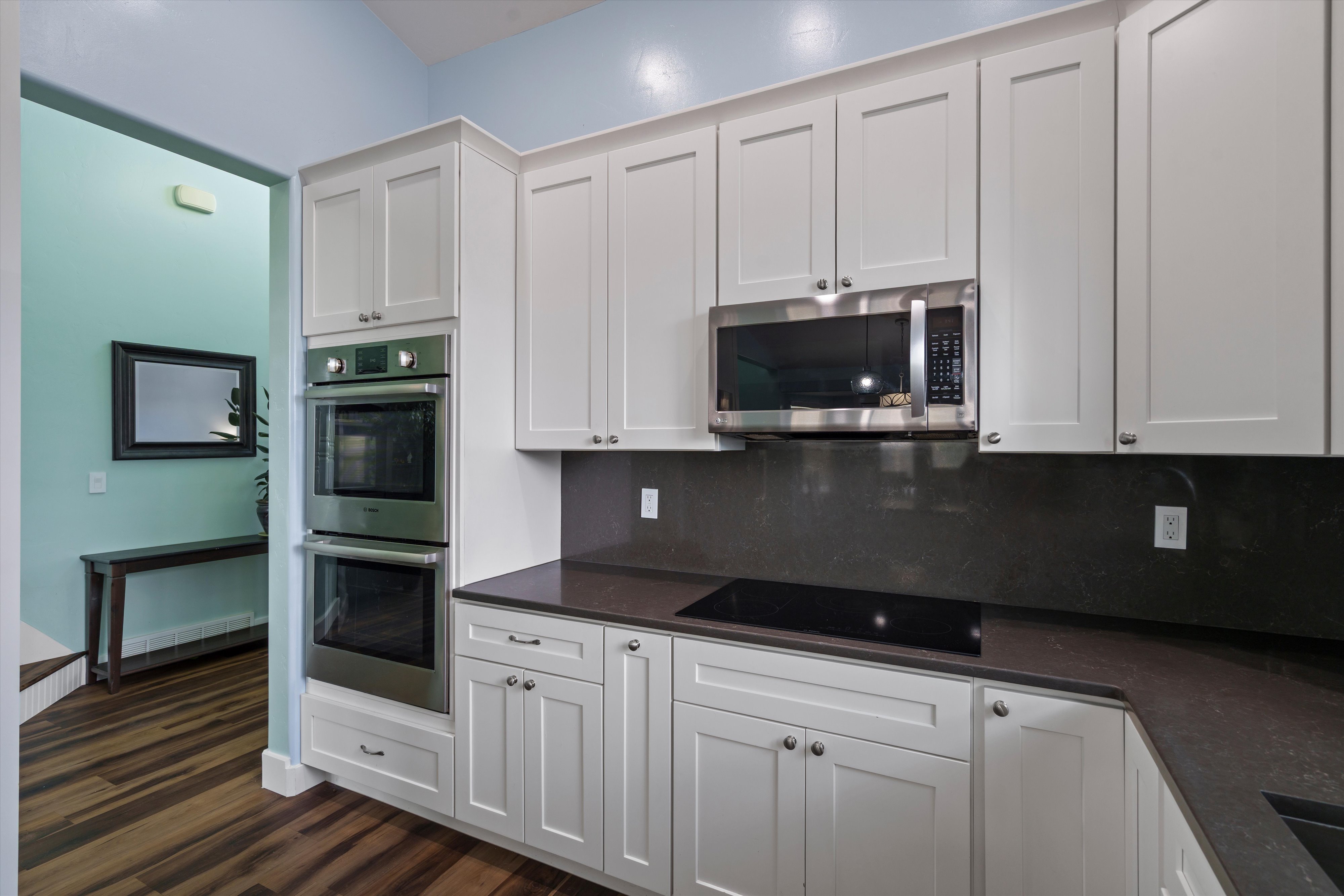 Modern kitchen featuring white shaker cabinetry, stainless steel double wall ovens, a built-in microwave, and a black cooktop