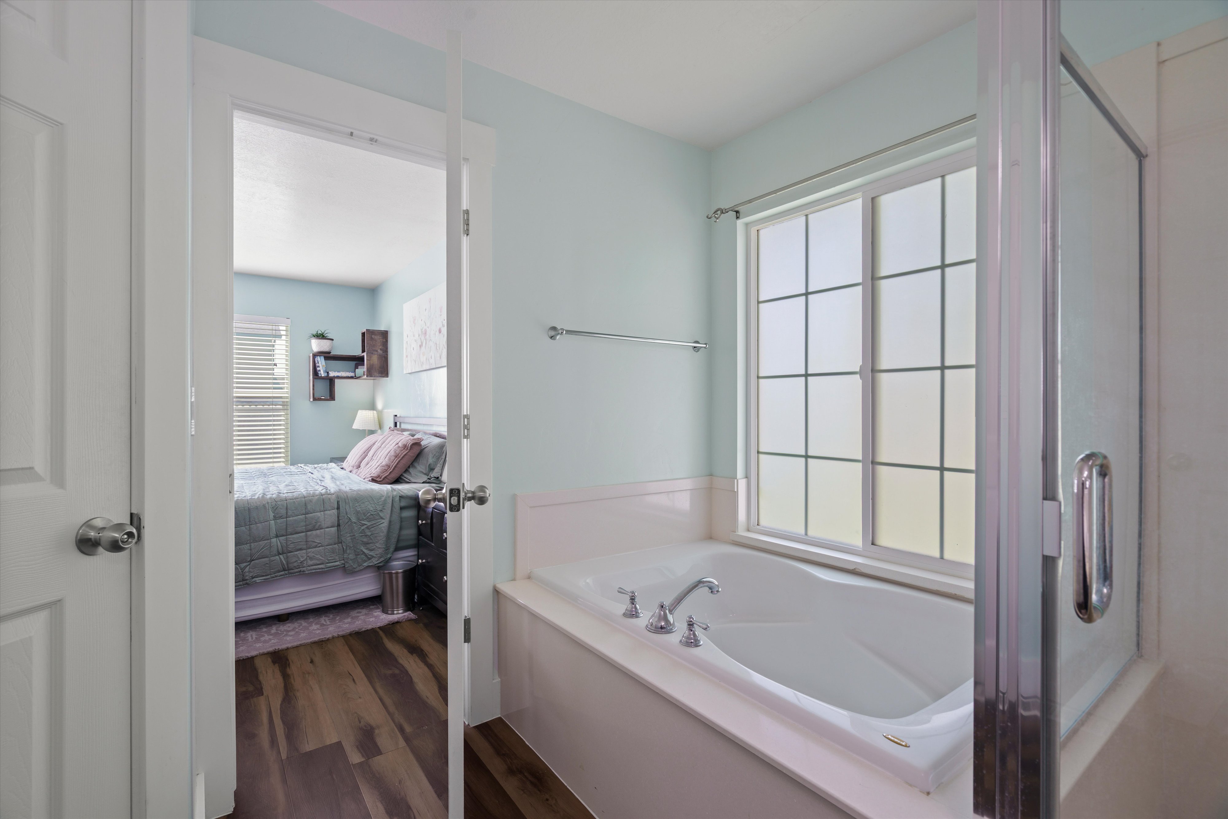 Soaking tub with chrome fixtures, framed by a window with grid patterns