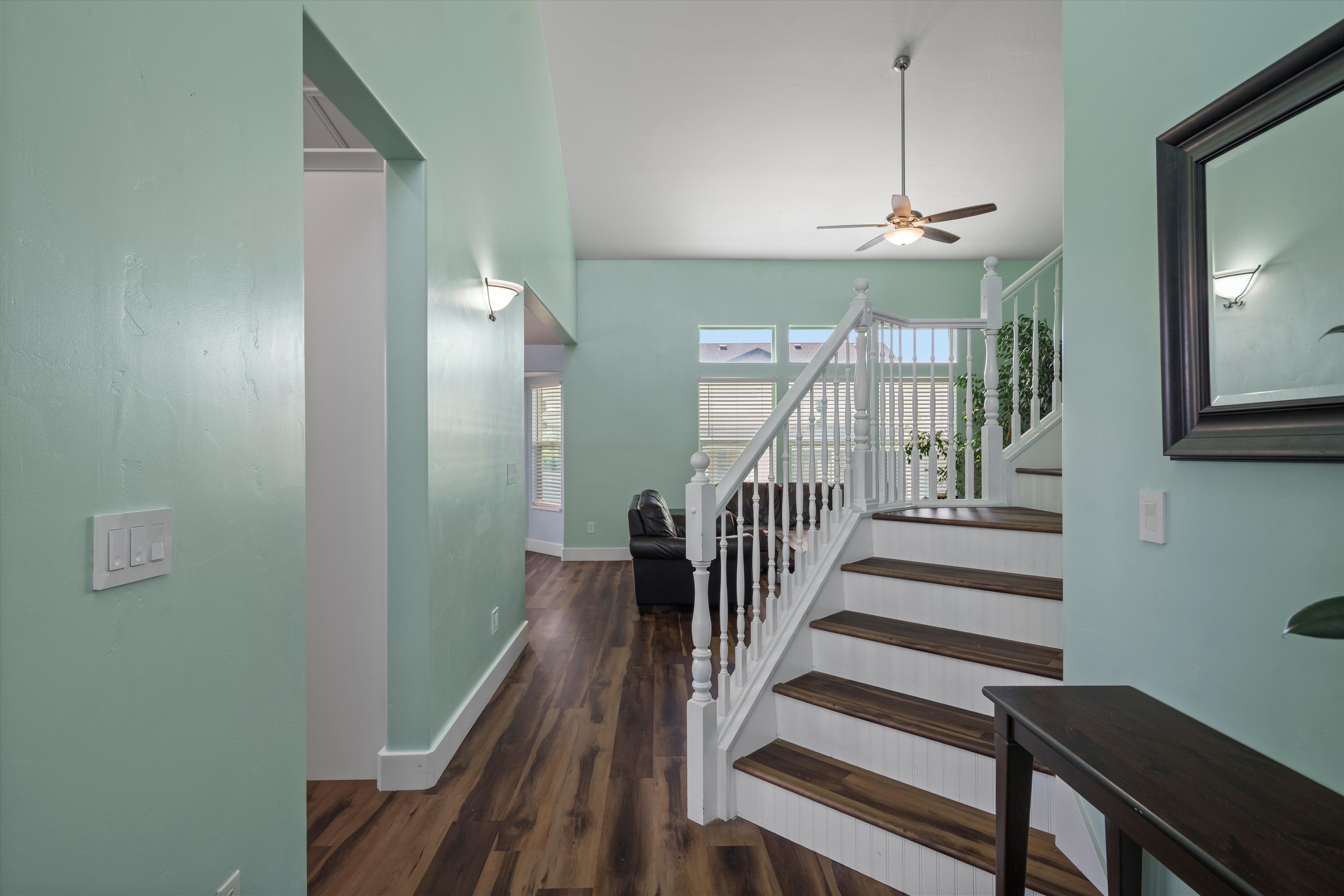 Entryway featuring a white banister staircase with wood-finish treads and risers, wood-finish flooring, and light green walls