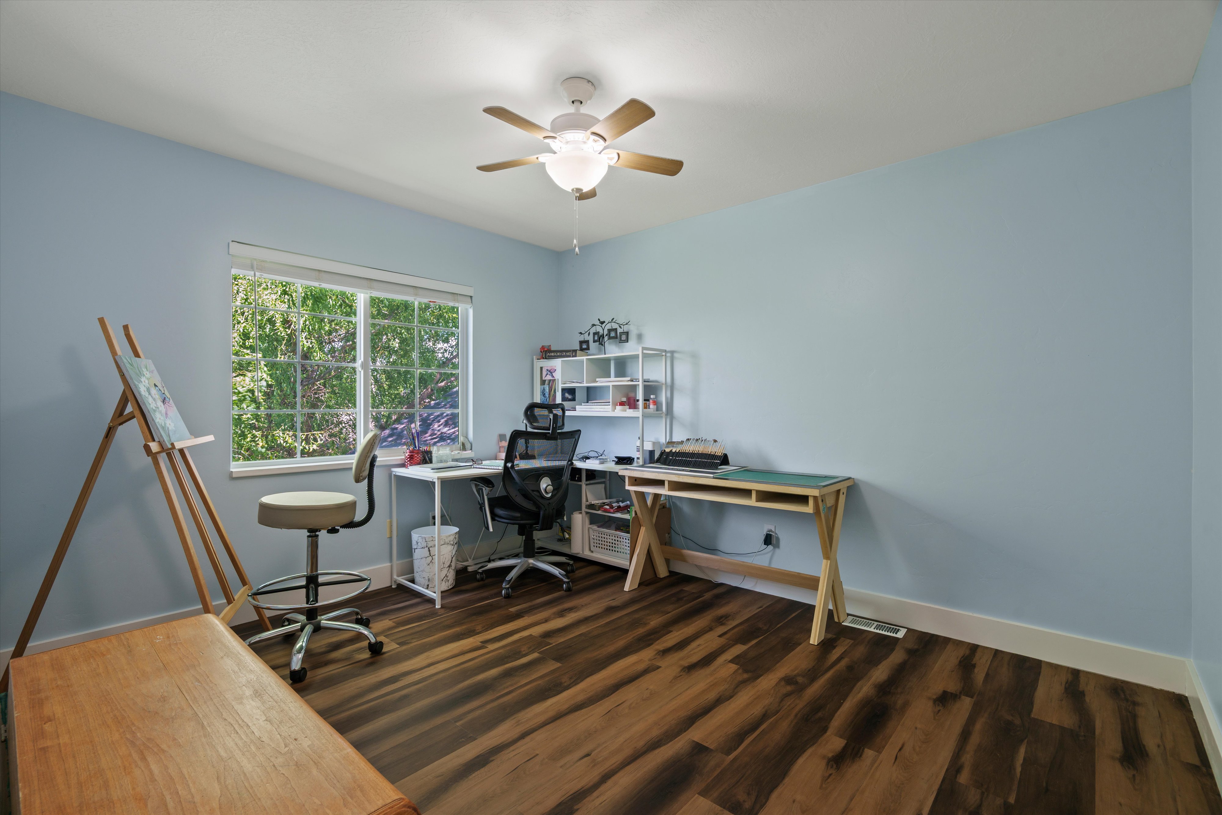 Room featuring wood-finish flooring, a window offering natural light, and a ceiling fan with integrated lighting