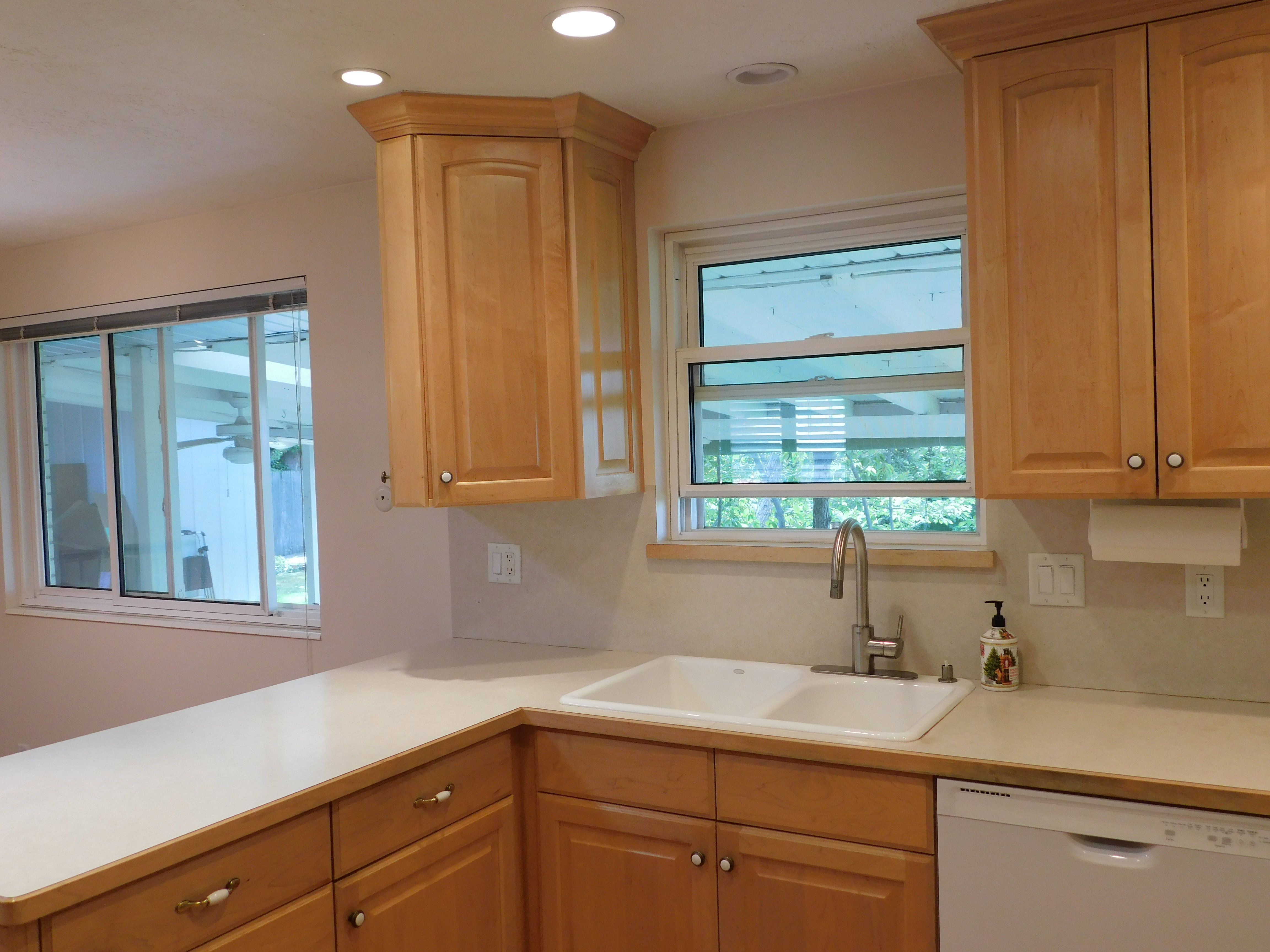 Kitchen featuring light wood cabinetry with brushed nickel hardware, white countertops, and a double basin sink with a gooseneck faucet