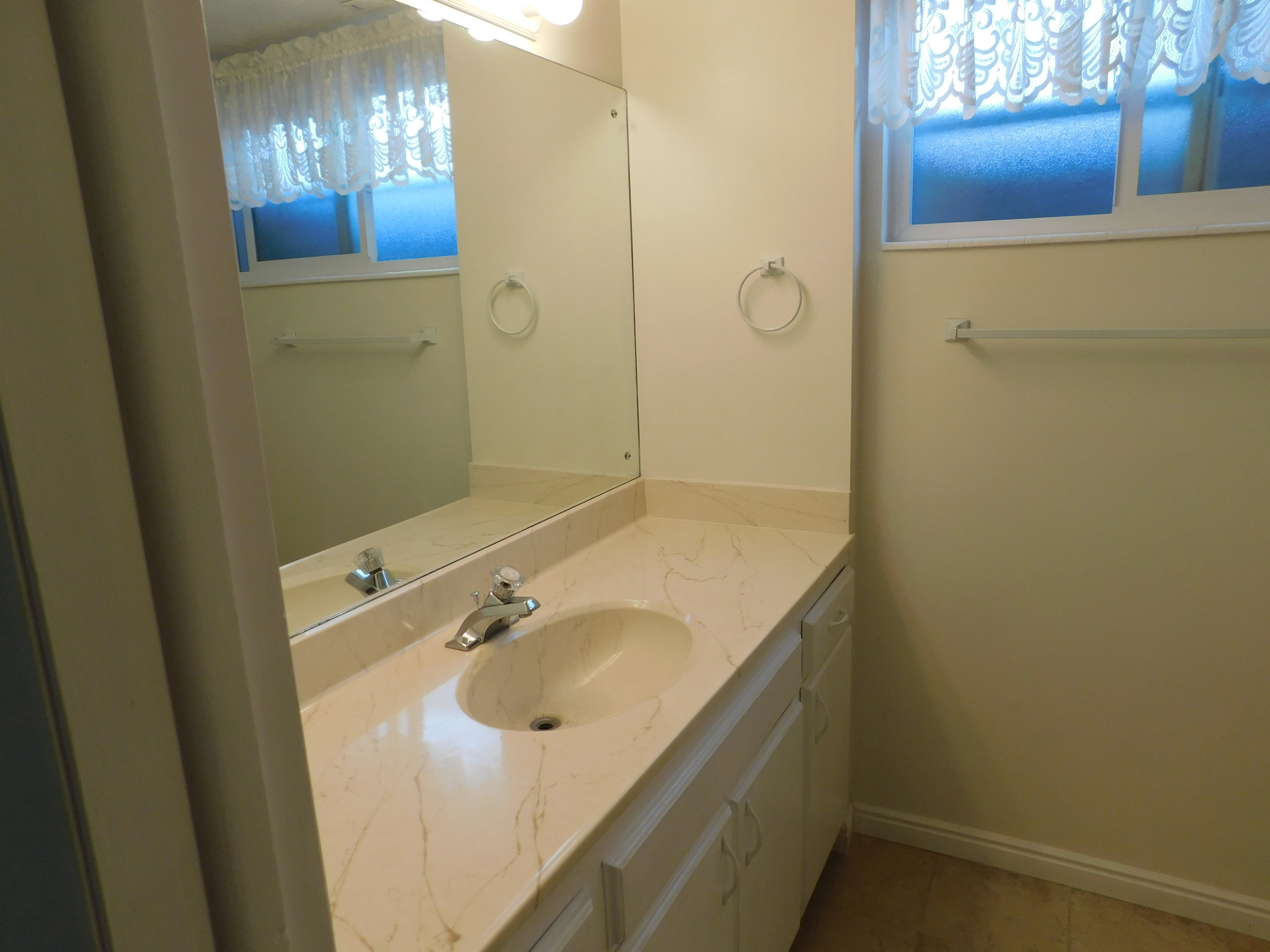 Bathroom vanity featuring a built-in oval sink with a chrome faucet, set into a stone-finish countertop