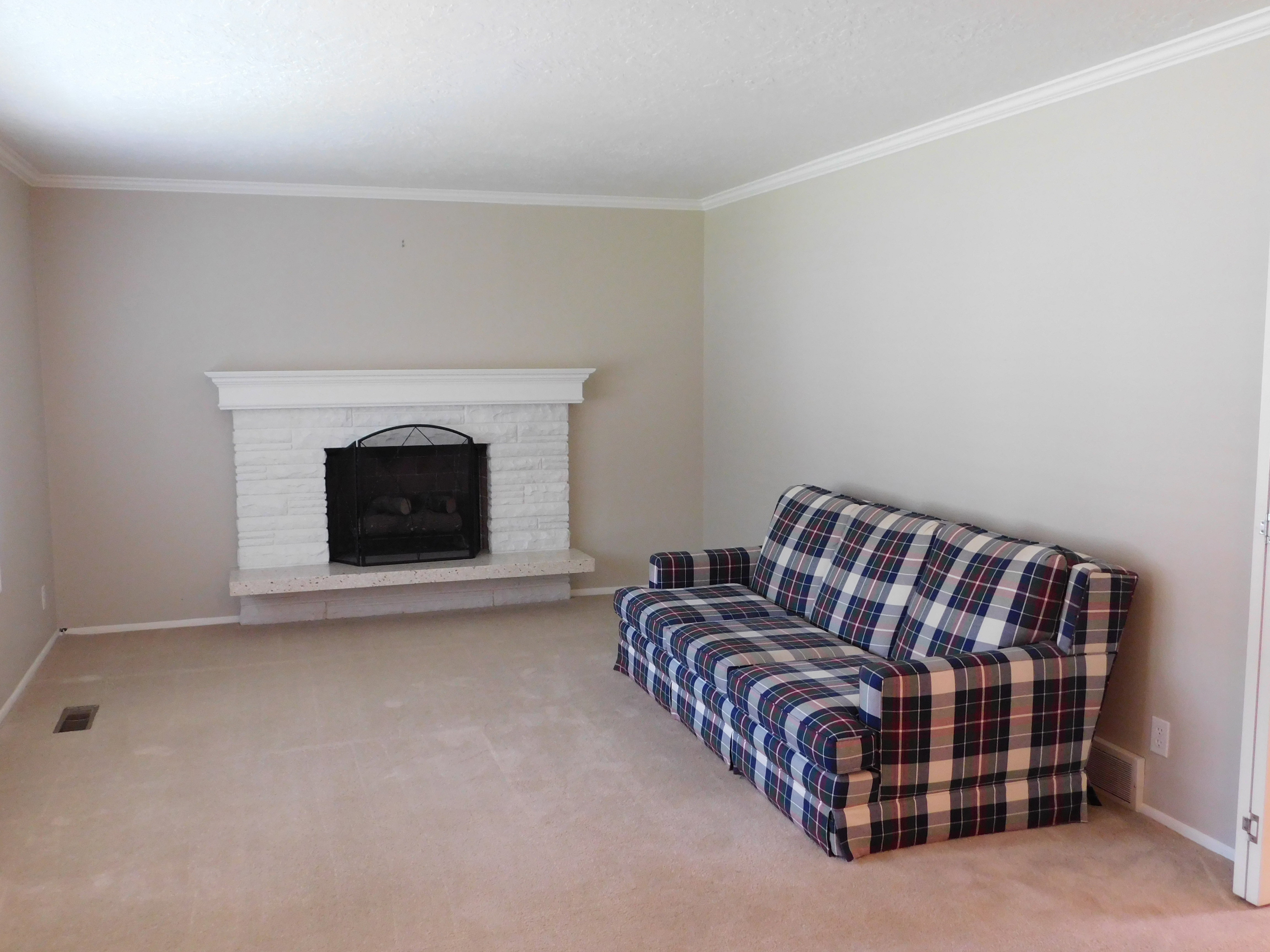 Living area featuring a painted brick fireplace with a white mantel and a stone hearth