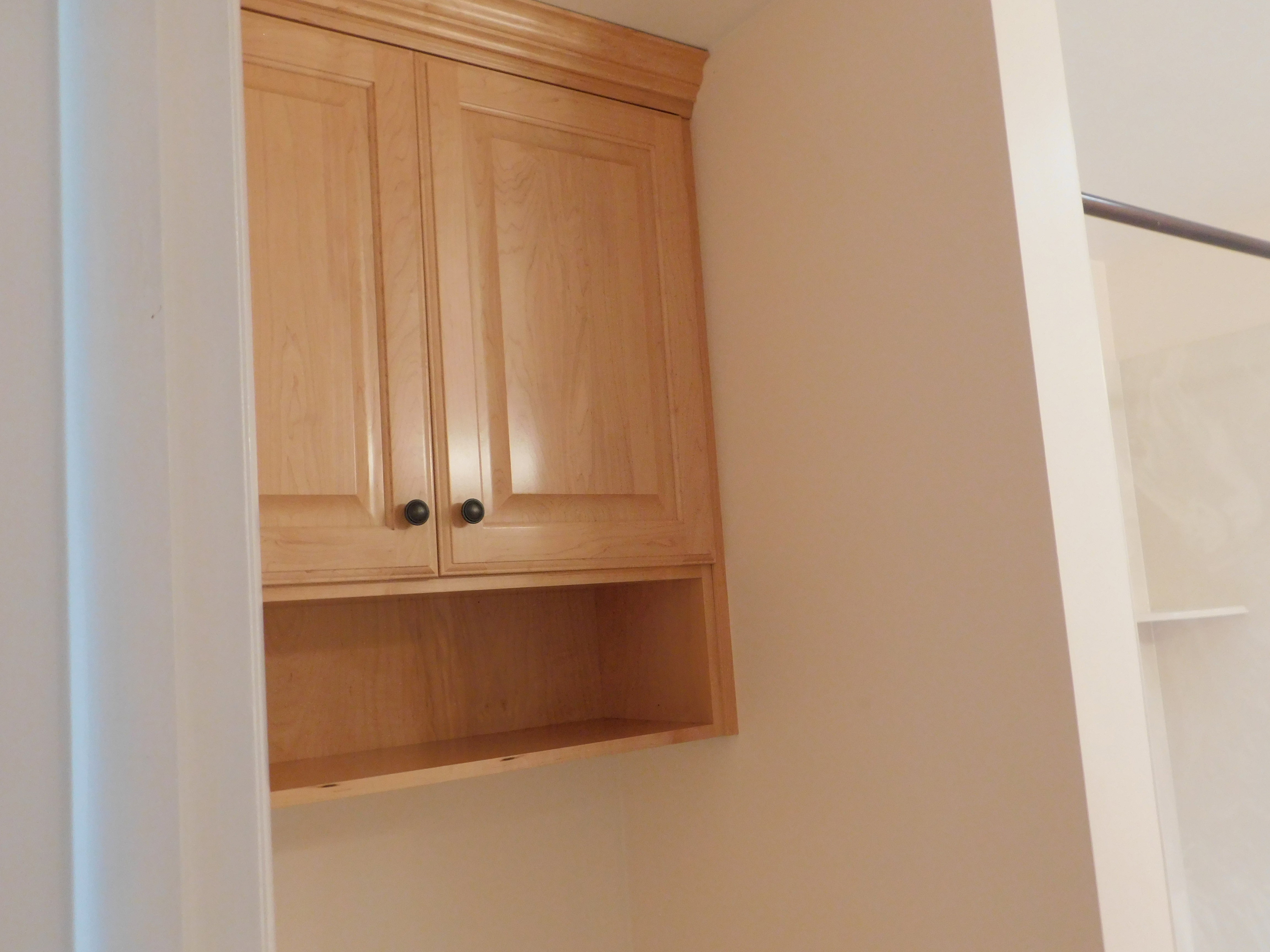 Light wood-finish cabinetry with crown molding and black hardware