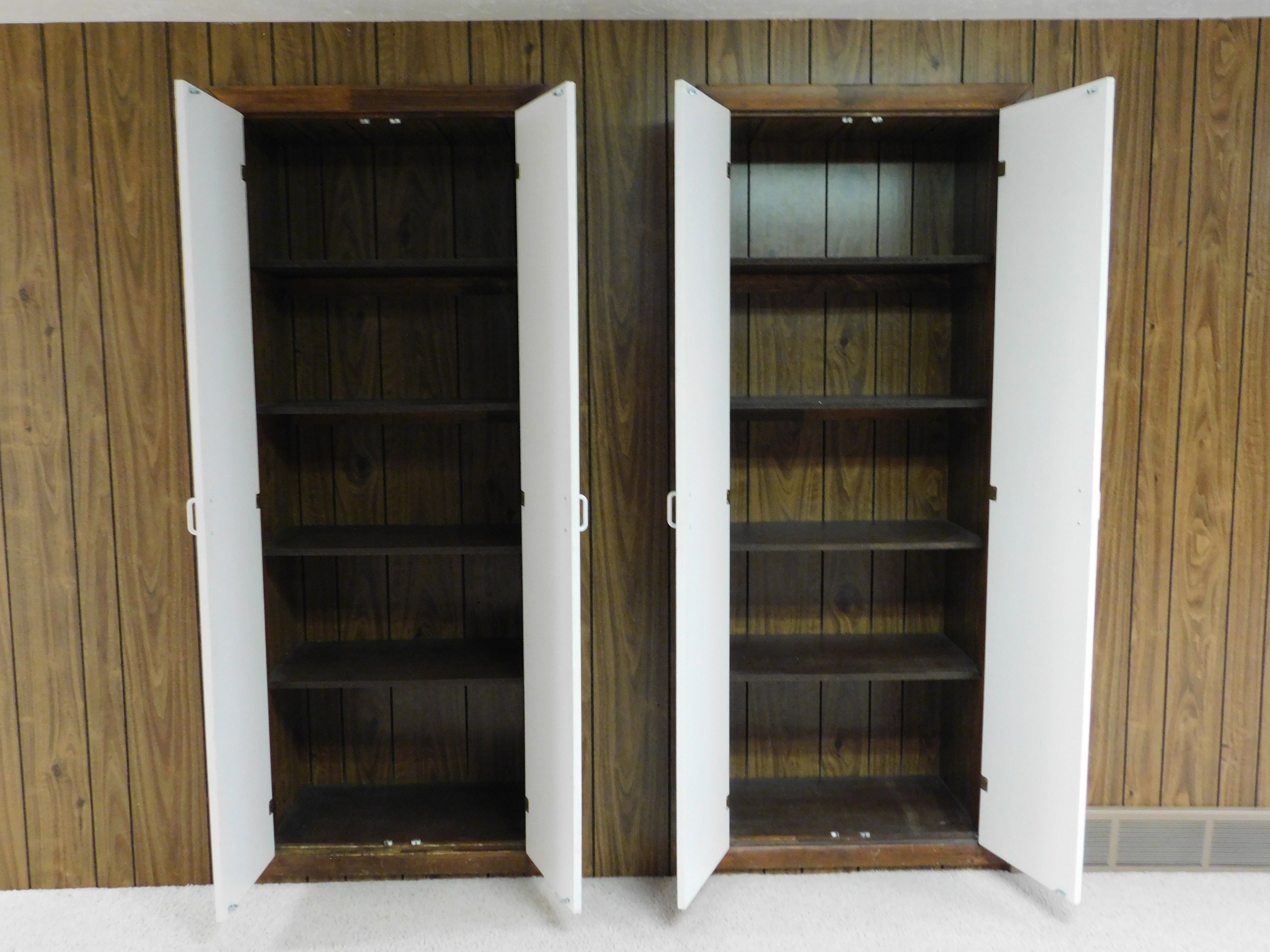 Two wood-finish storage cabinets with white doors and interior shelving