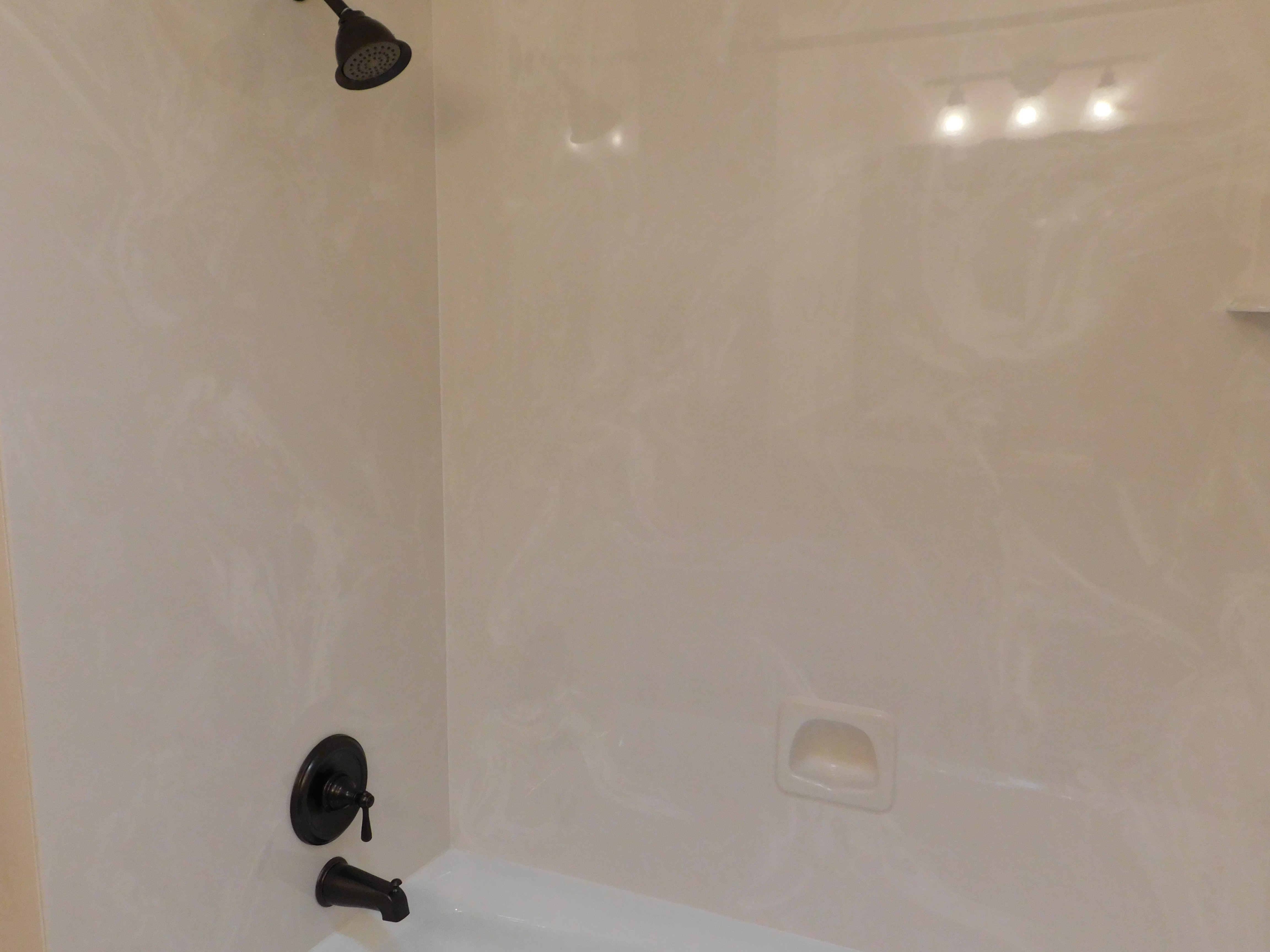 Tub and shower combination featuring oil-rubbed bronze fixtures and a built-in soap dish