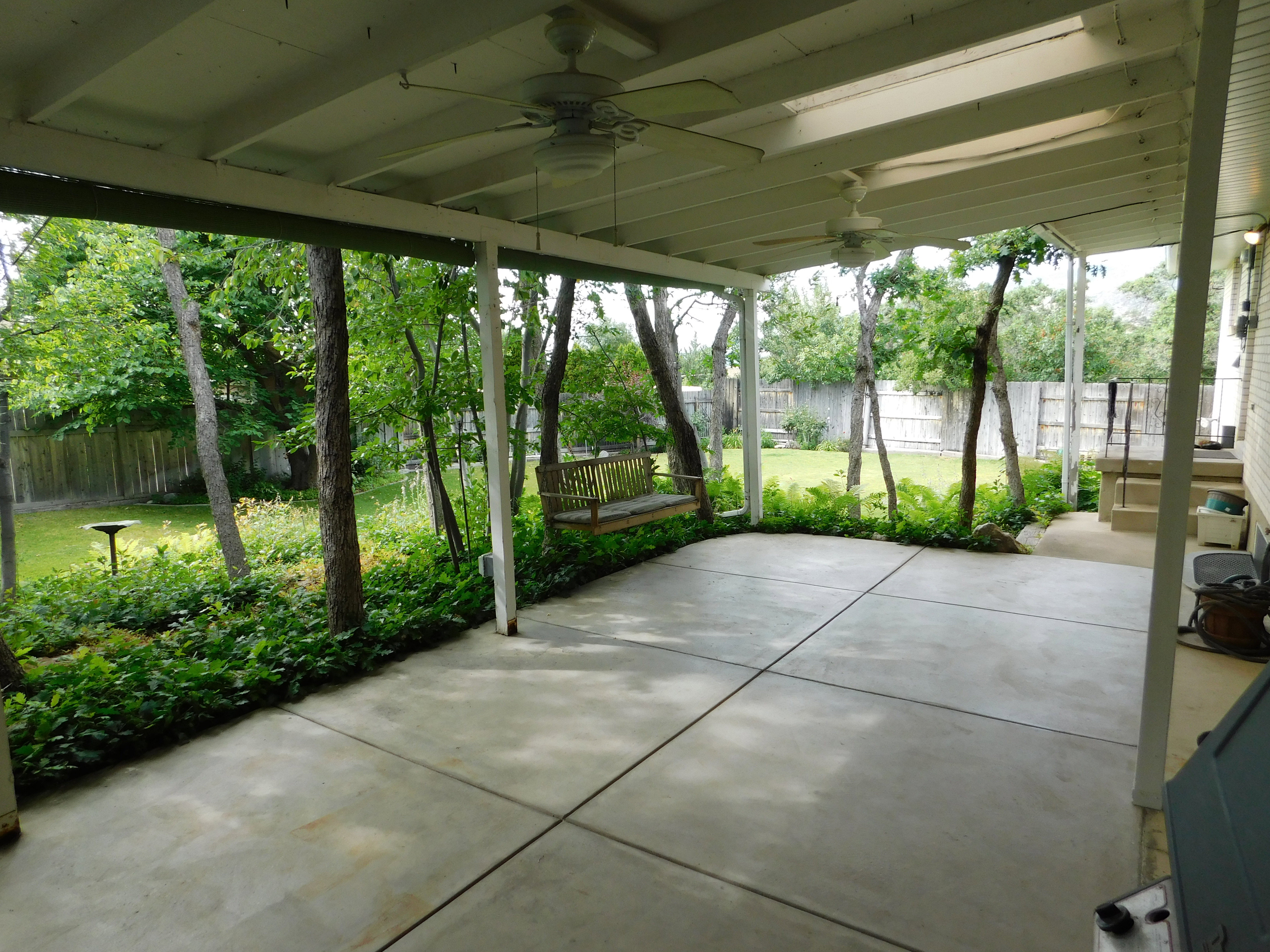 Covered patio with a concrete slab, exposed beam ceiling, and two ceiling fans