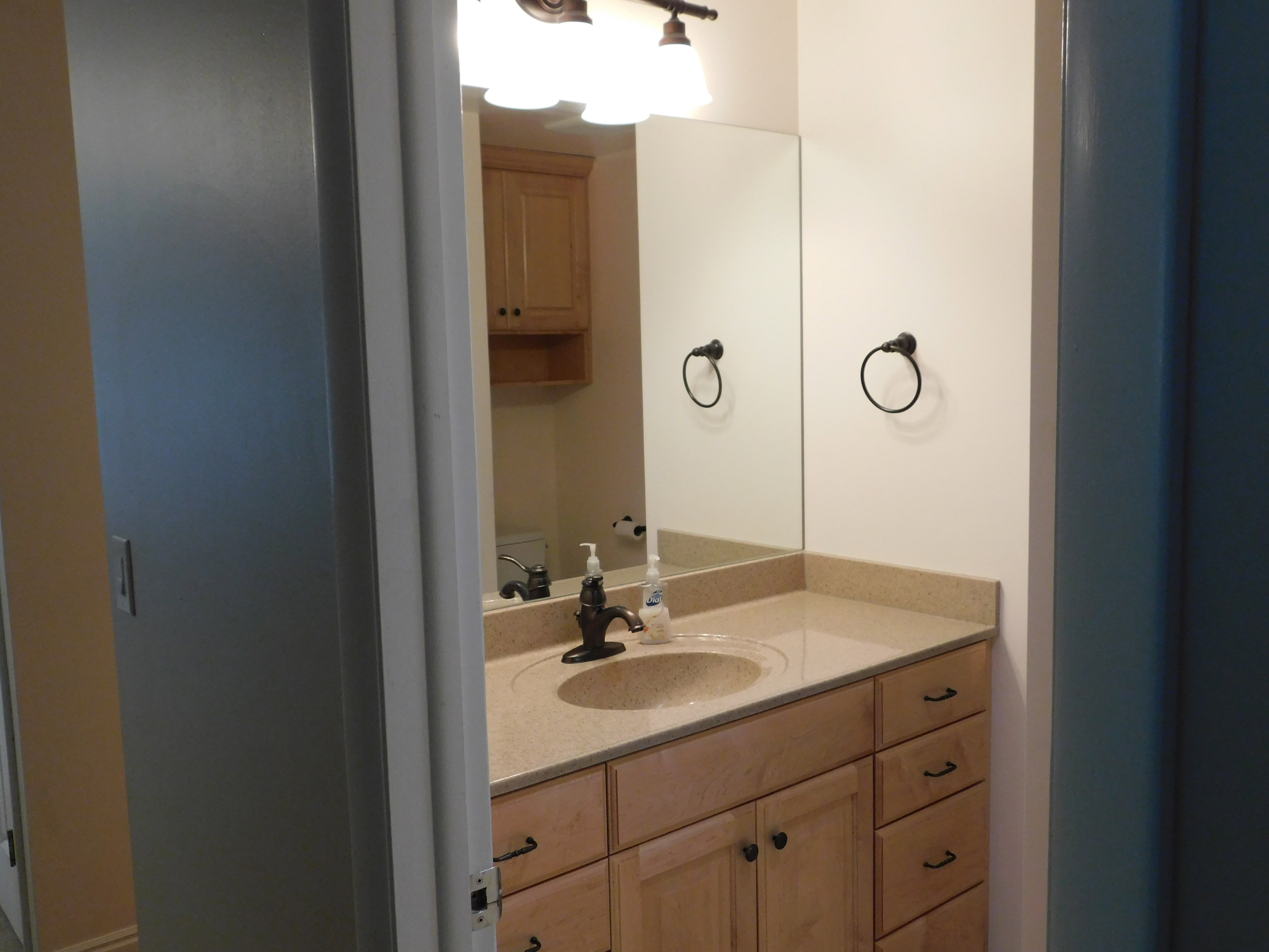 Bathroom featuring a single vanity with light-toned cabinetry, a built-in sink, and a light-colored countertop