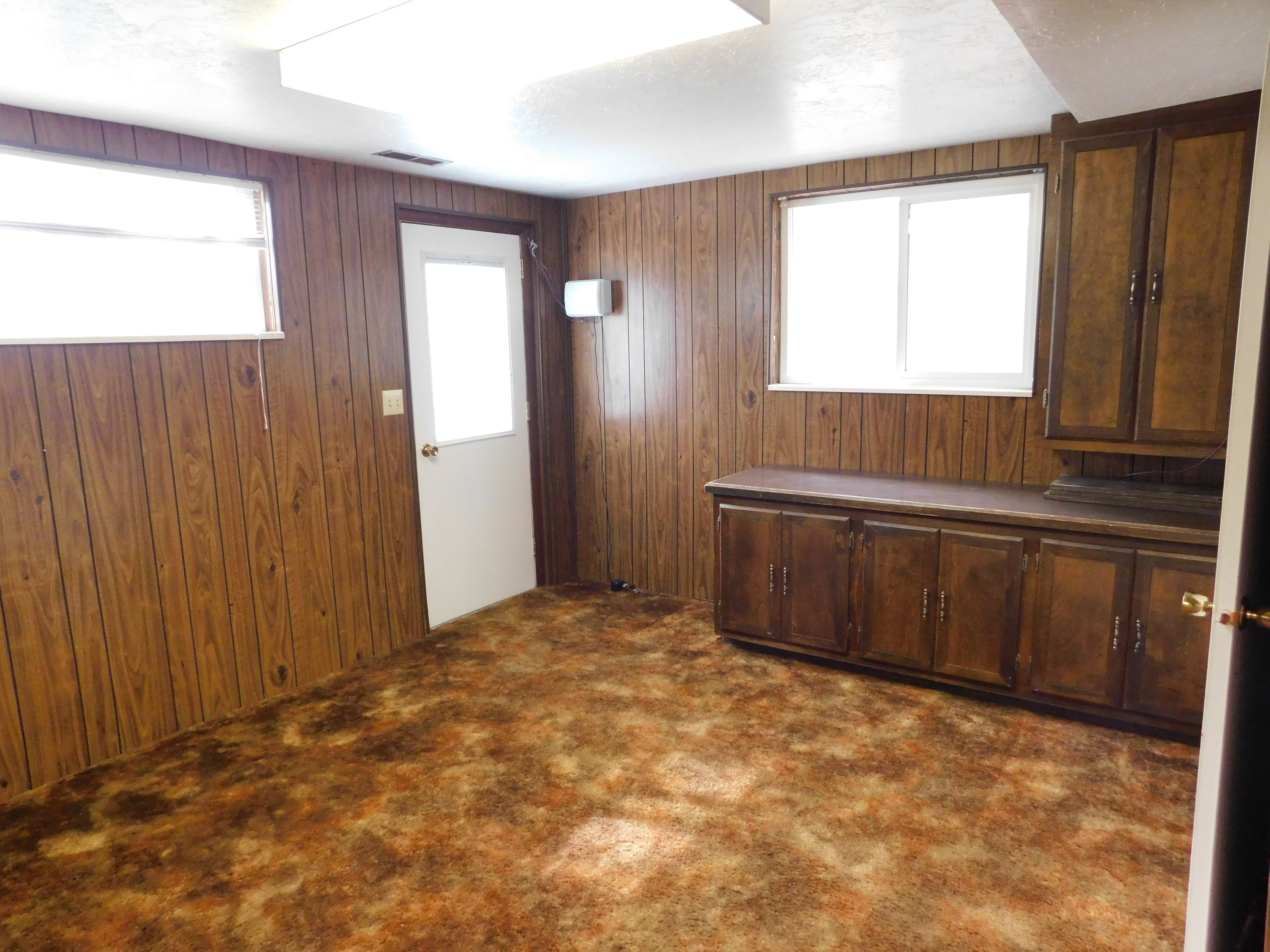 Interior room featuring wood-panel walls, patterned carpet, and multiple windows
