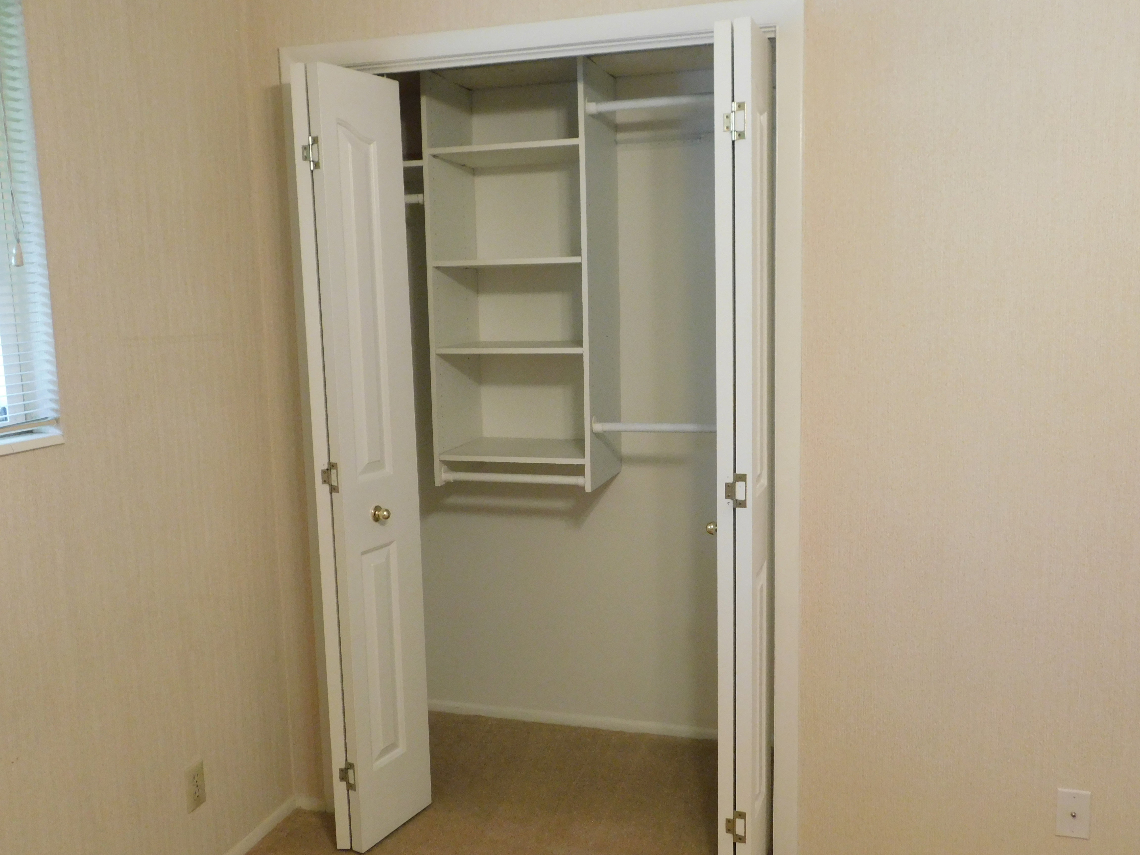 Closet with bi-fold doors, built-in shelving, and hanging rods