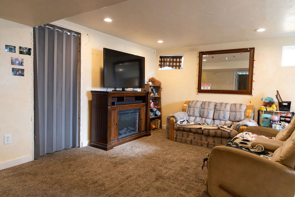 Carpeted recreation room featuring an entertainment center with an integrated electric fireplace, recessed ceiling lighting, and a window with blinds