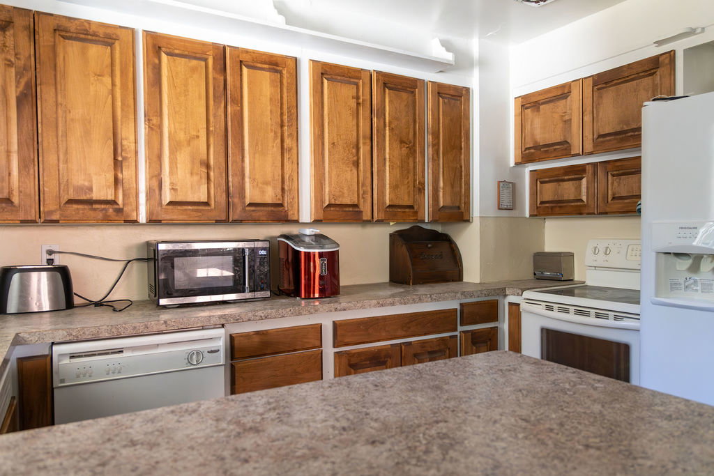 Kitchen featuring wood-finish cabinetry, patterned countertops, a built-in dishwasher, and a white electric range
