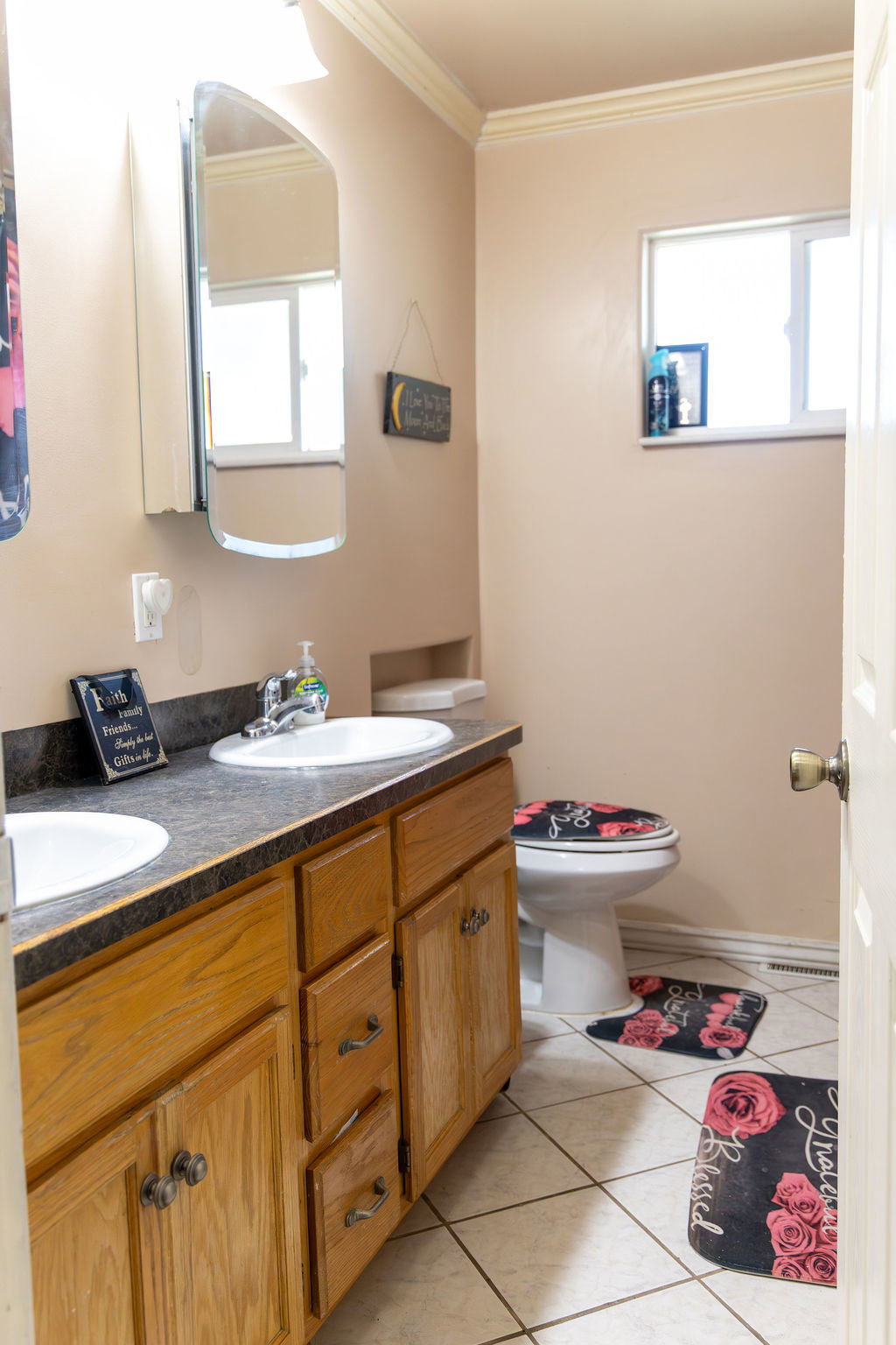 Dual basin vanity with wood cabinetry and dark countertops