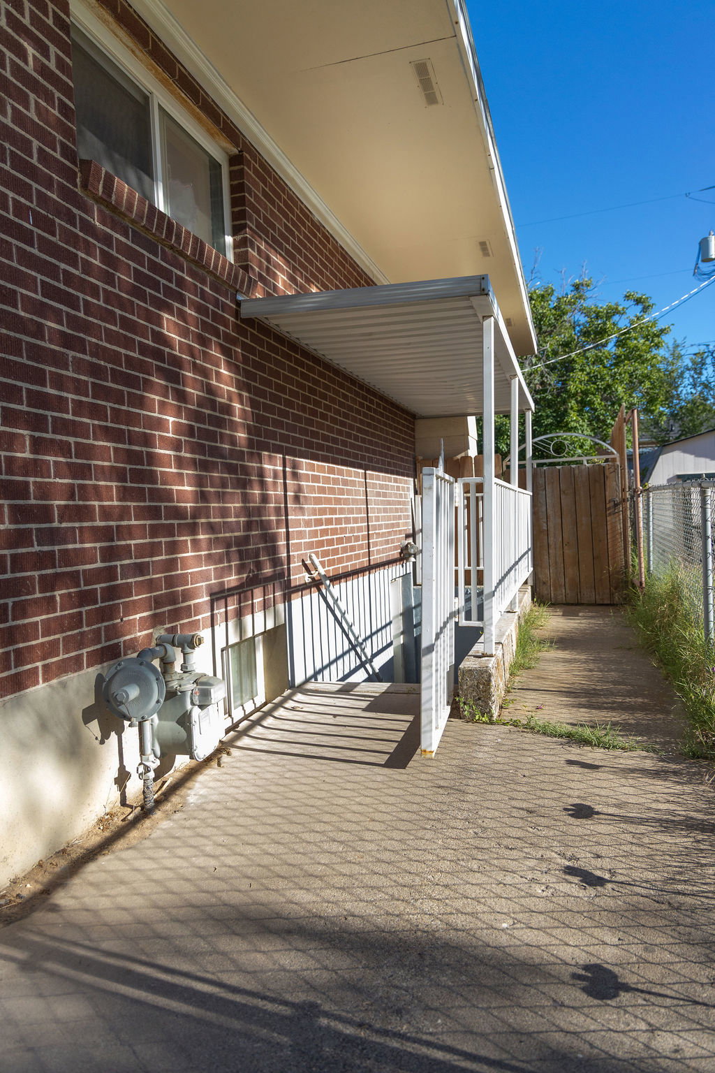 Brick exterior featuring a covered porch with a metal awning and white railing