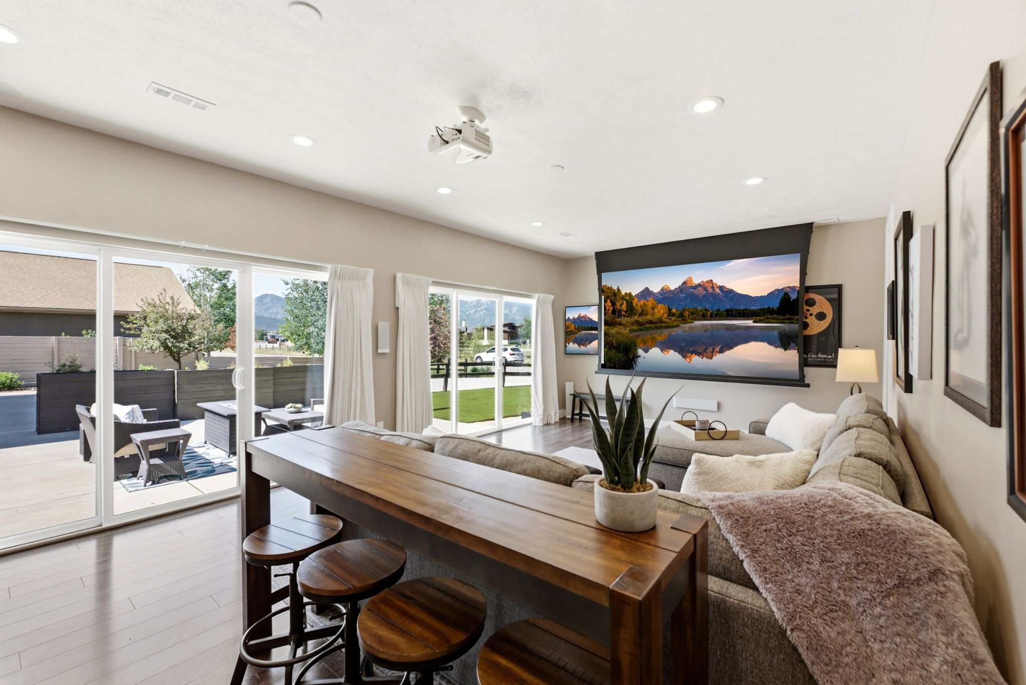 Spacious entertainment area featuring a retractable projection screen, recessed lighting, and wood-finish flooring