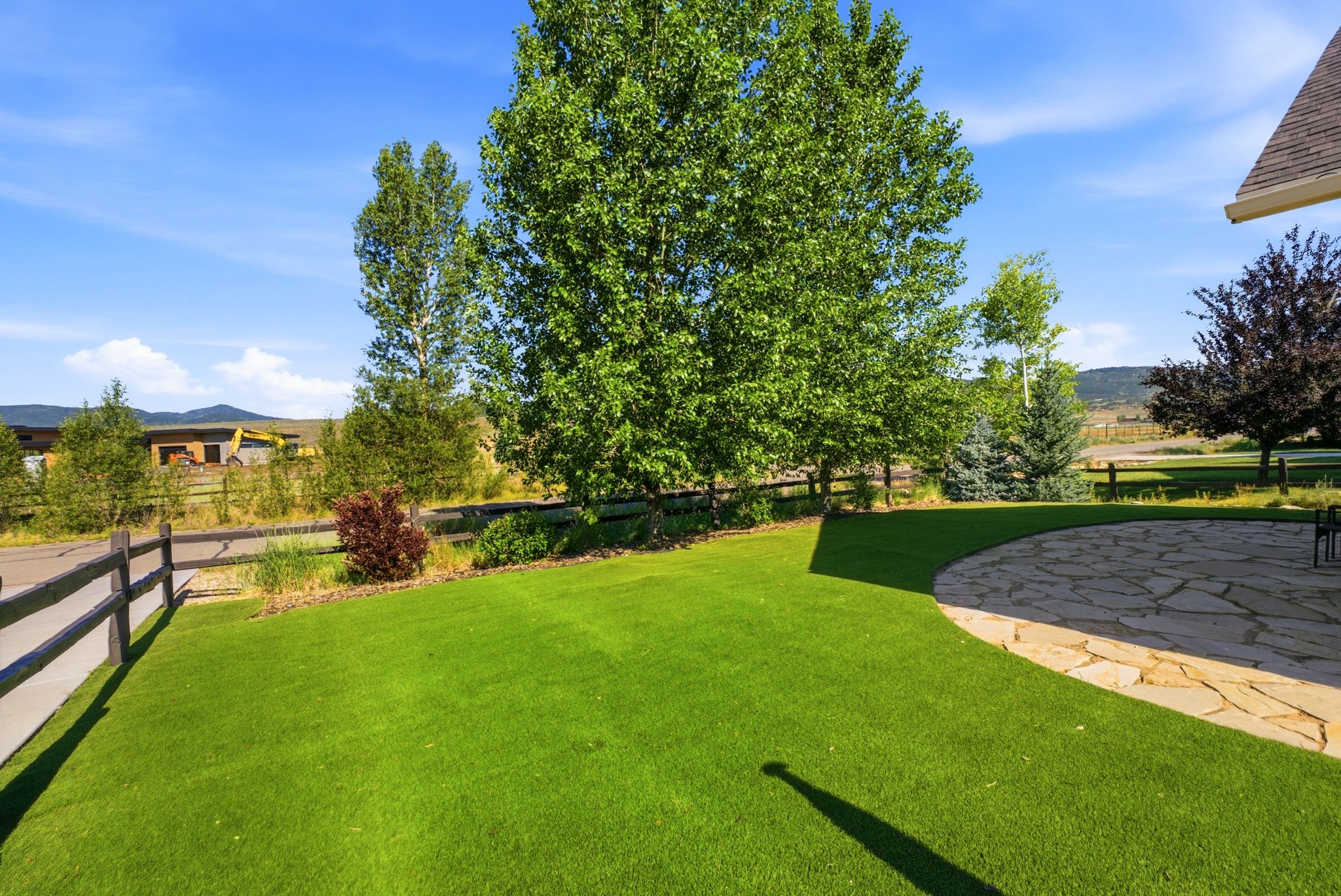 Expansive green lawn with a curved flagstone patio