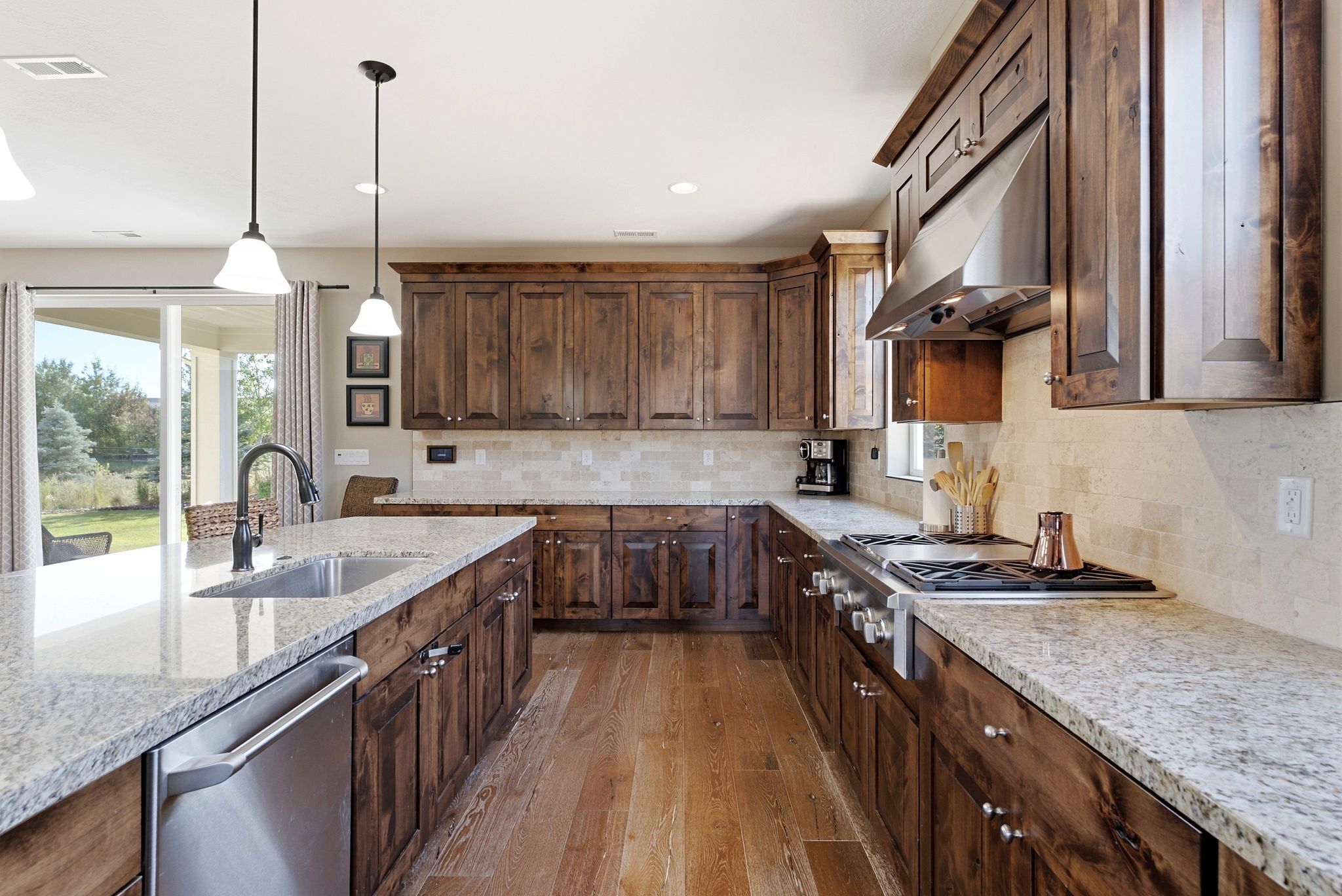Kitchen featuring wood-finish cabinetry, light-toned granite countertops, and a subway tile backsplash