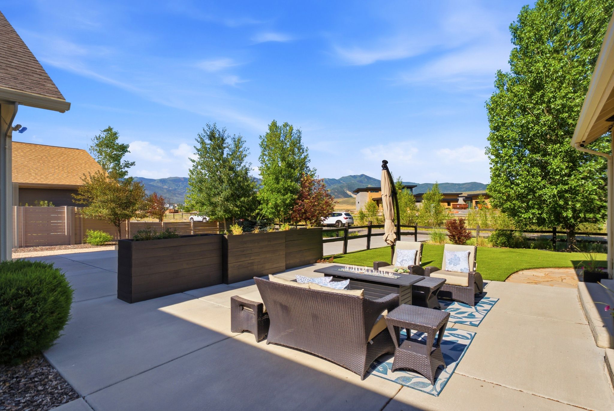 Expansive concrete patio with integrated planter boxes and a manicured lawn area