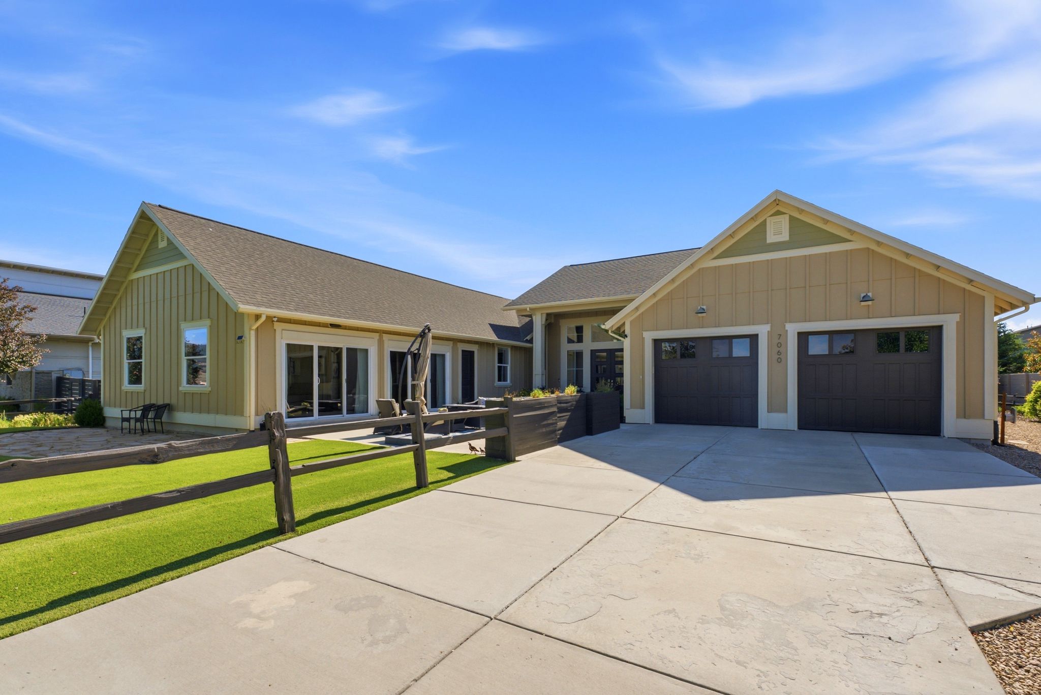 Craftsman-style exterior featuring a spacious concrete driveway, an attached double garage with dark wood-look doors, and board-and-batten siding