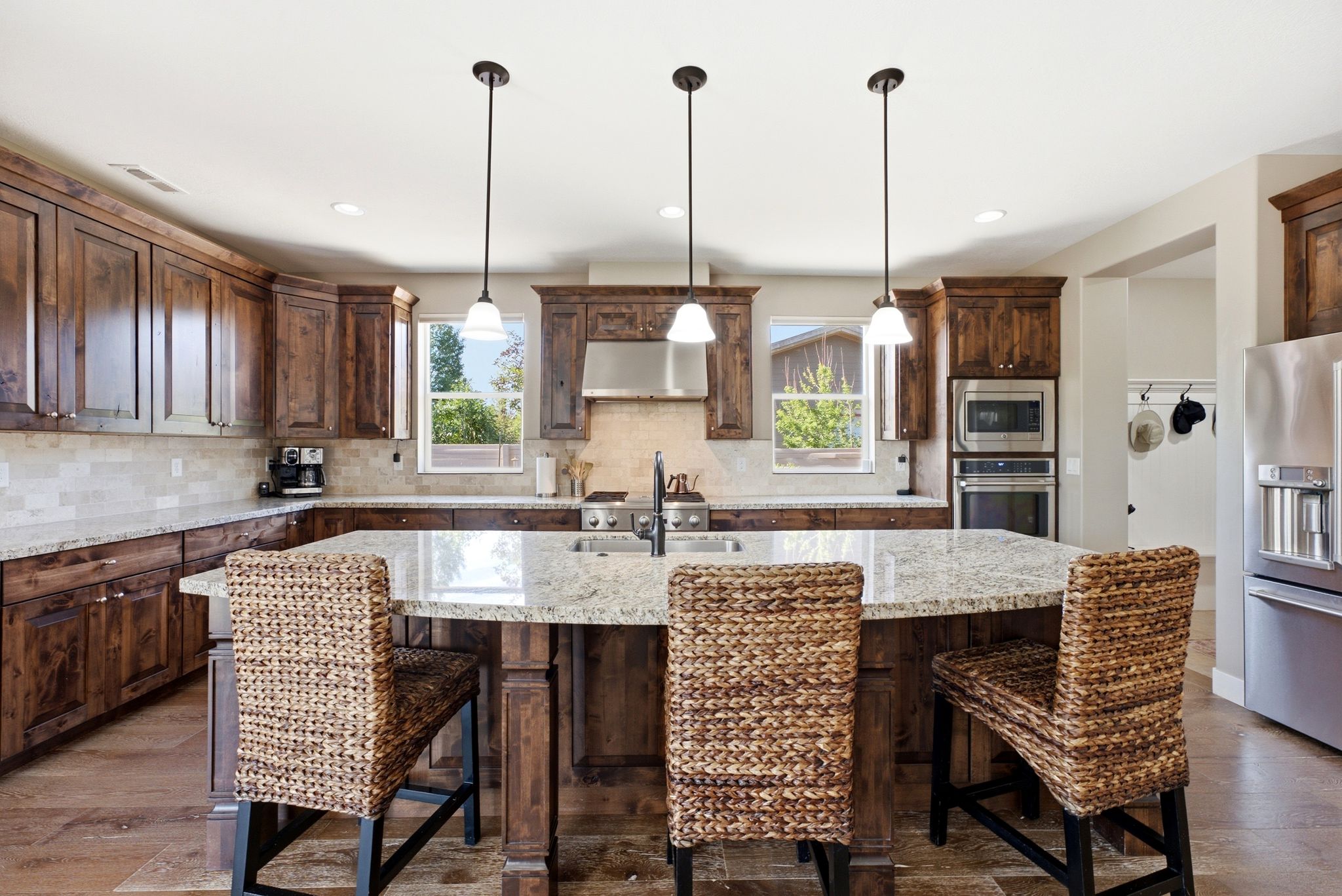 Spacious kitchen featuring rich wood cabinetry, granite countertops, and a large island with pendant lighting
