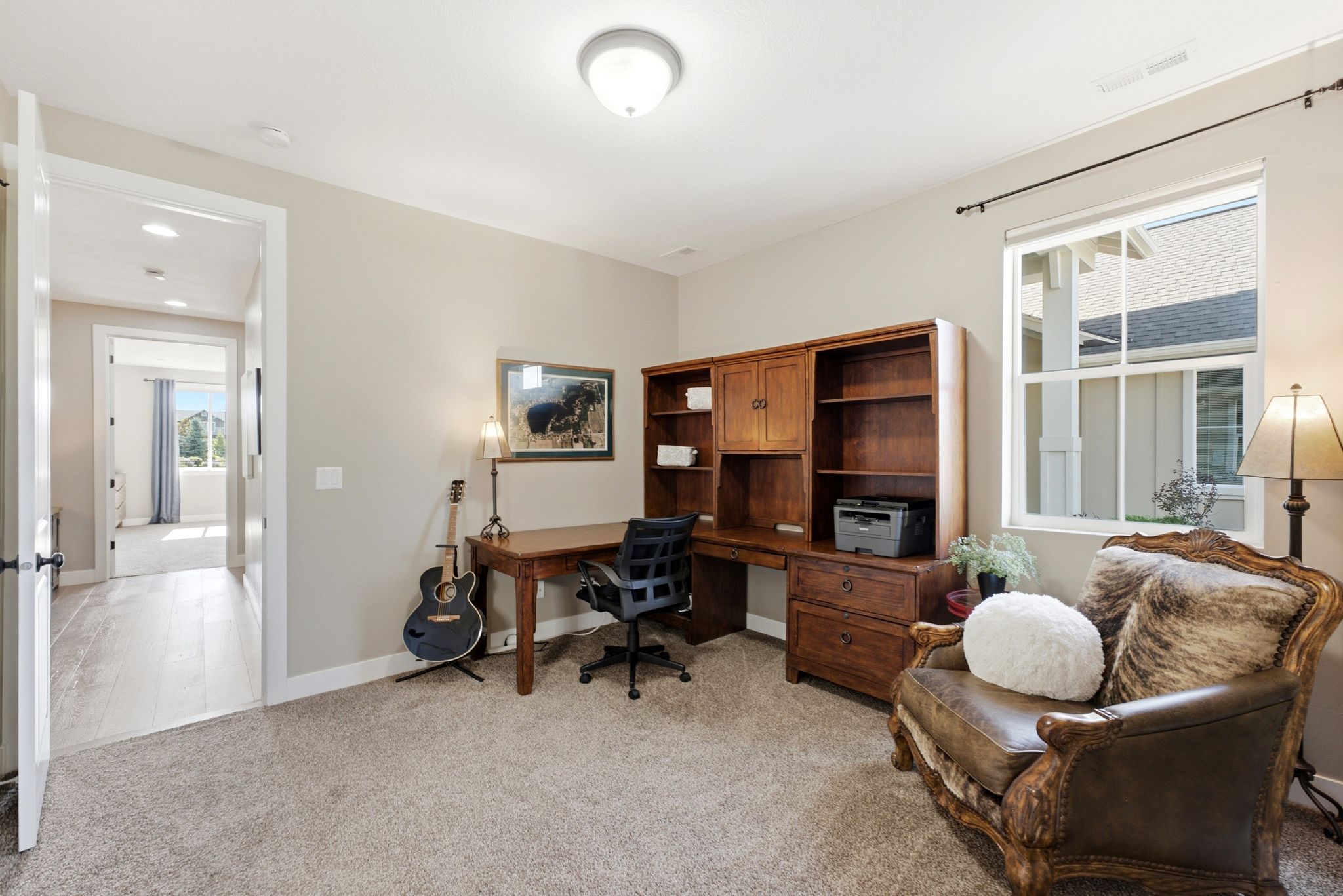 Room featuring a built-in wood desk and shelving unit, carpeted flooring, and a large window with white trim