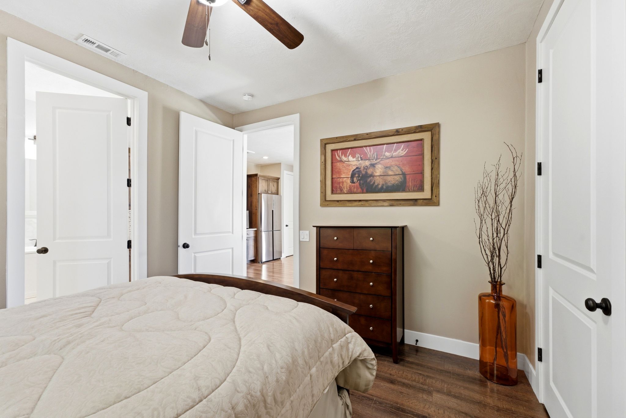 Interior room featuring wood-finish flooring, two-panel white doors with dark hardware, and light-toned wall paint