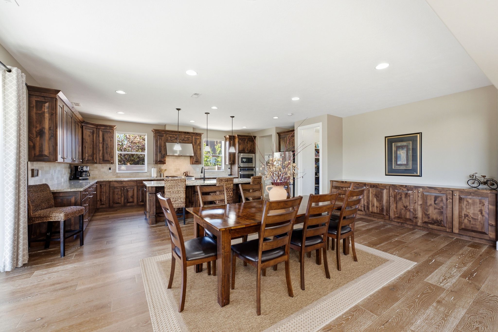Open-concept kitchen and dining area featuring wood-finish flooring, recessed lighting, and a neutral color palette