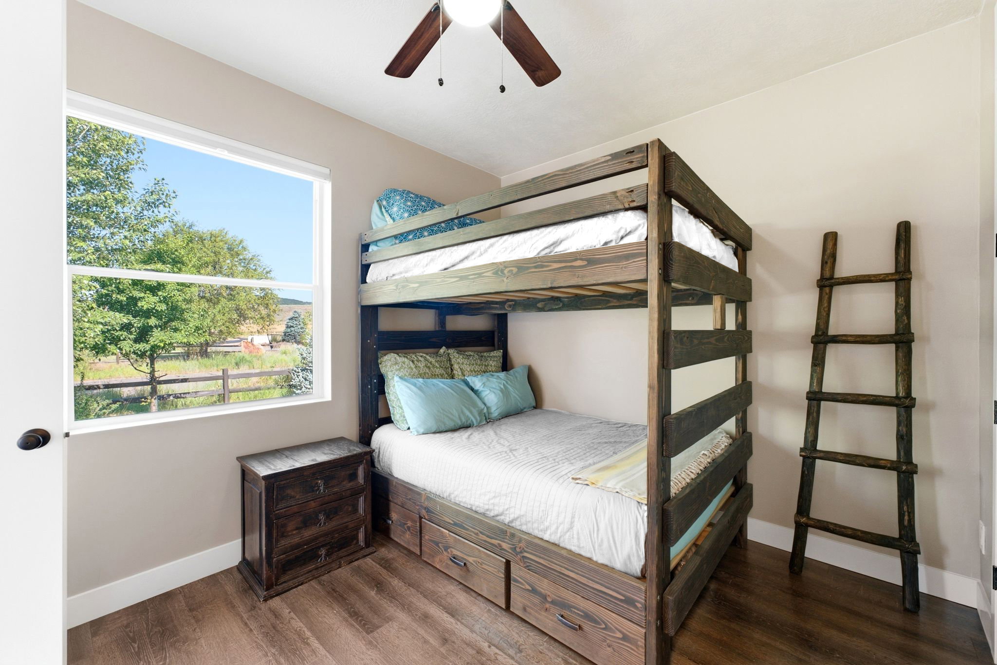Room featuring wood-finish flooring, a white-framed window, and a ceiling fan with integrated lighting