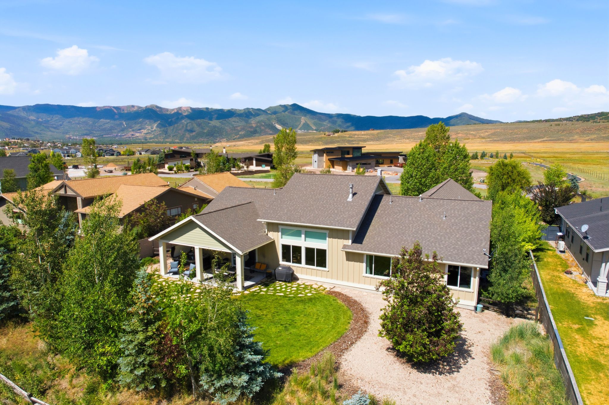 Contemporary residence featuring an expansive covered patio, mature landscaping, and a gravel pathway