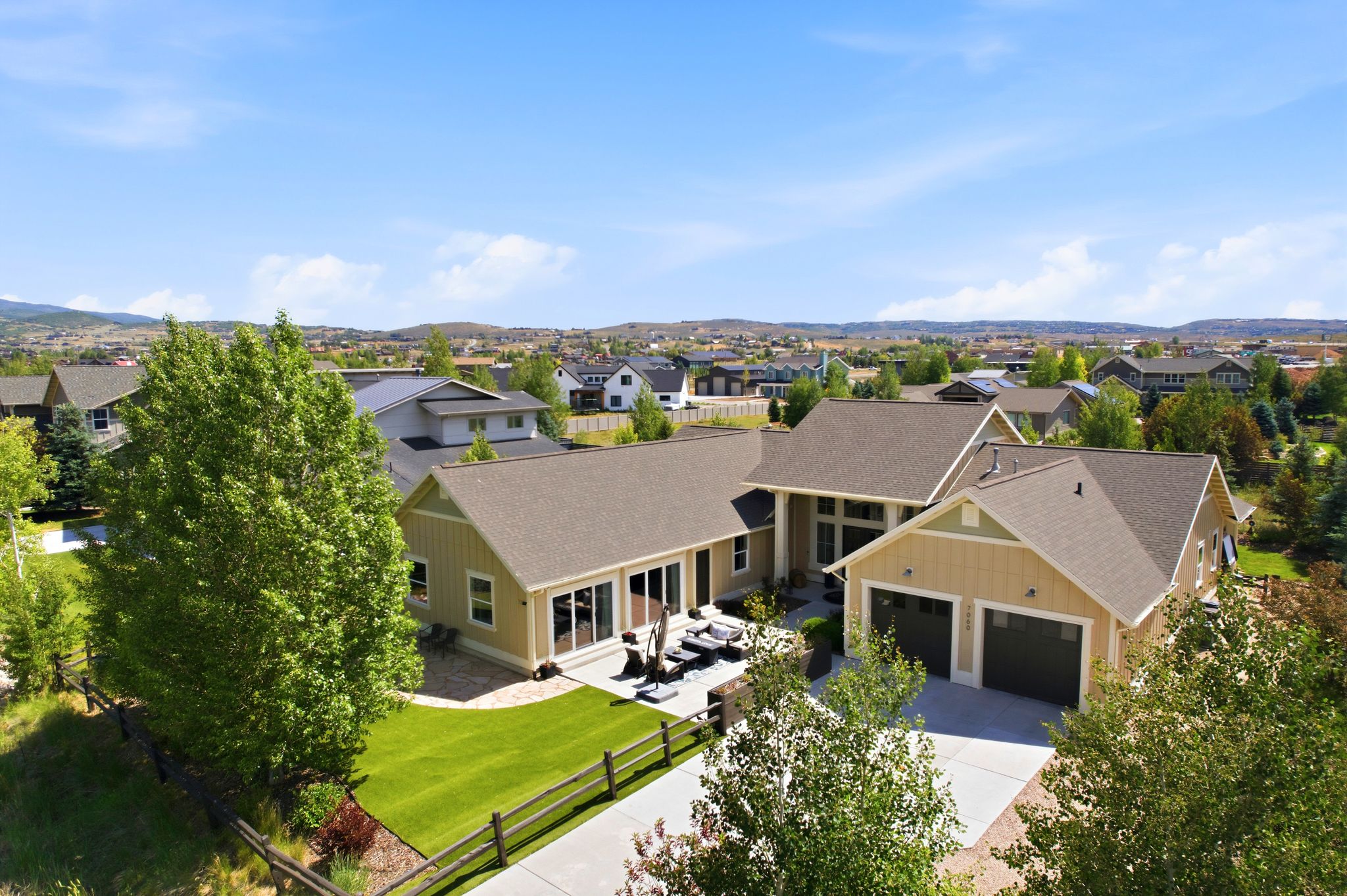 Contemporary residential property featuring a two-car garage, expansive concrete driveway, and a spacious rear patio area