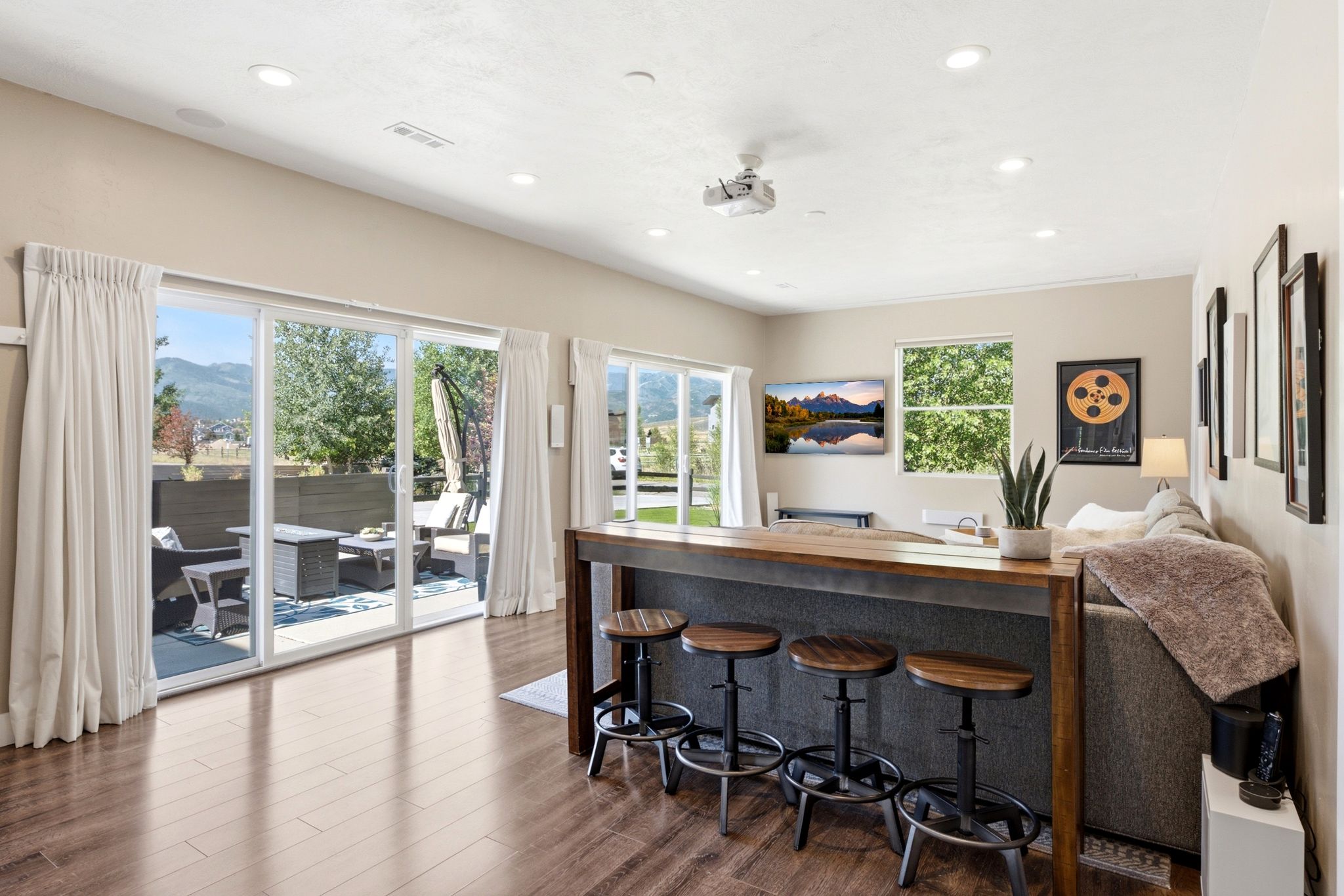 Spacious living area featuring wood-finish flooring, recessed lighting, and a projector