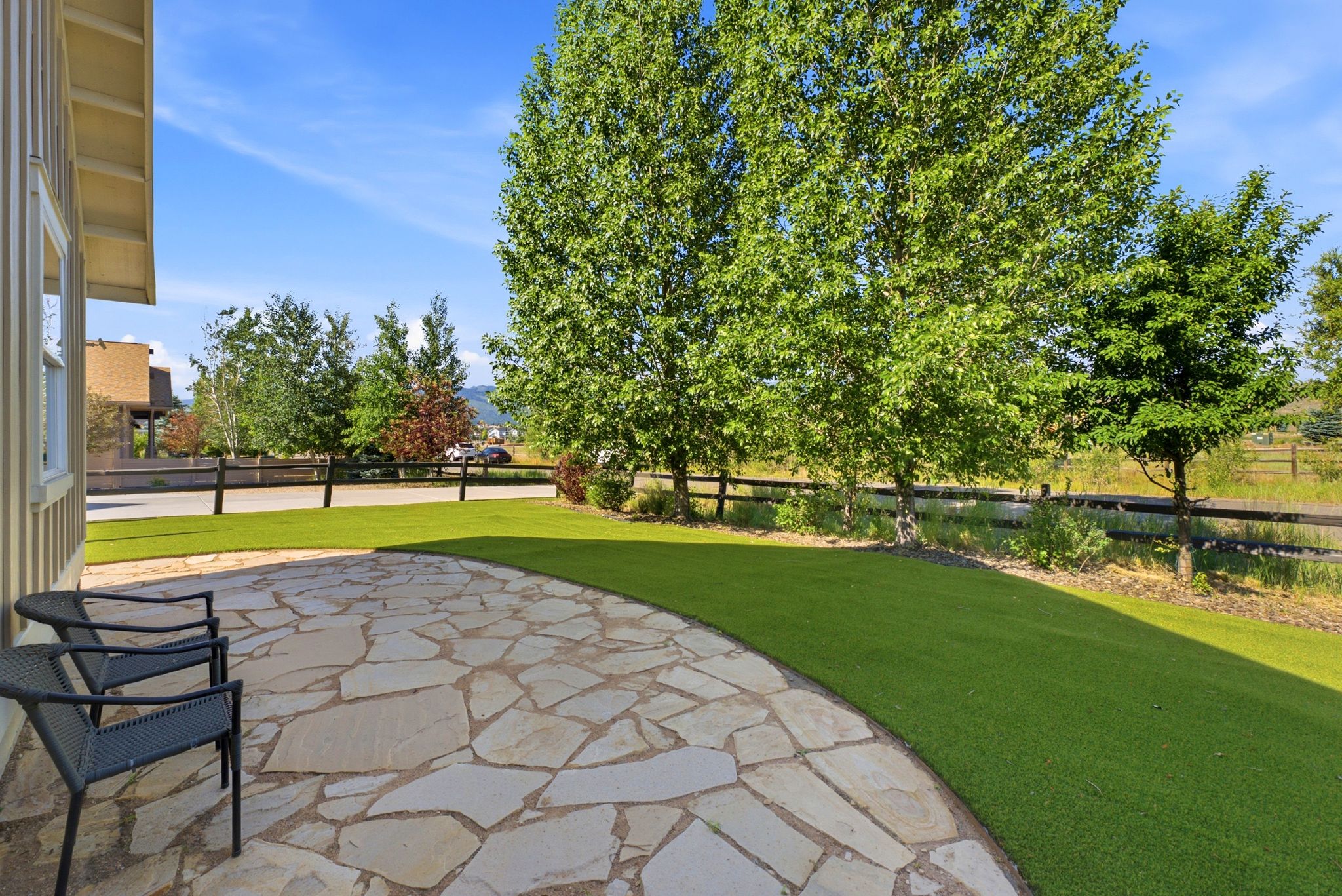 Curved flagstone patio with expansive green lawn