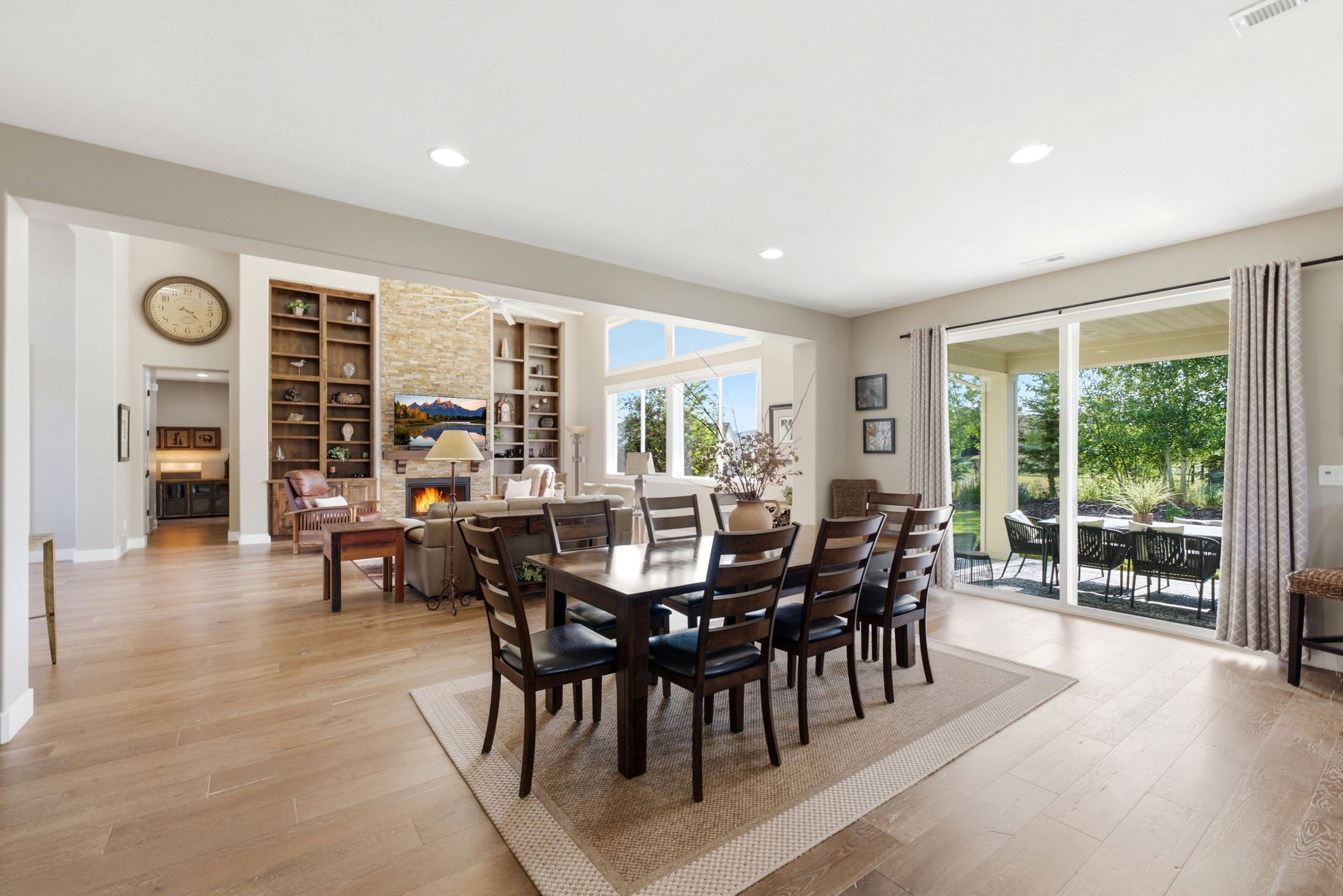 Expansive living area with wood-finish flooring, recessed lighting, and a stone-clad fireplace