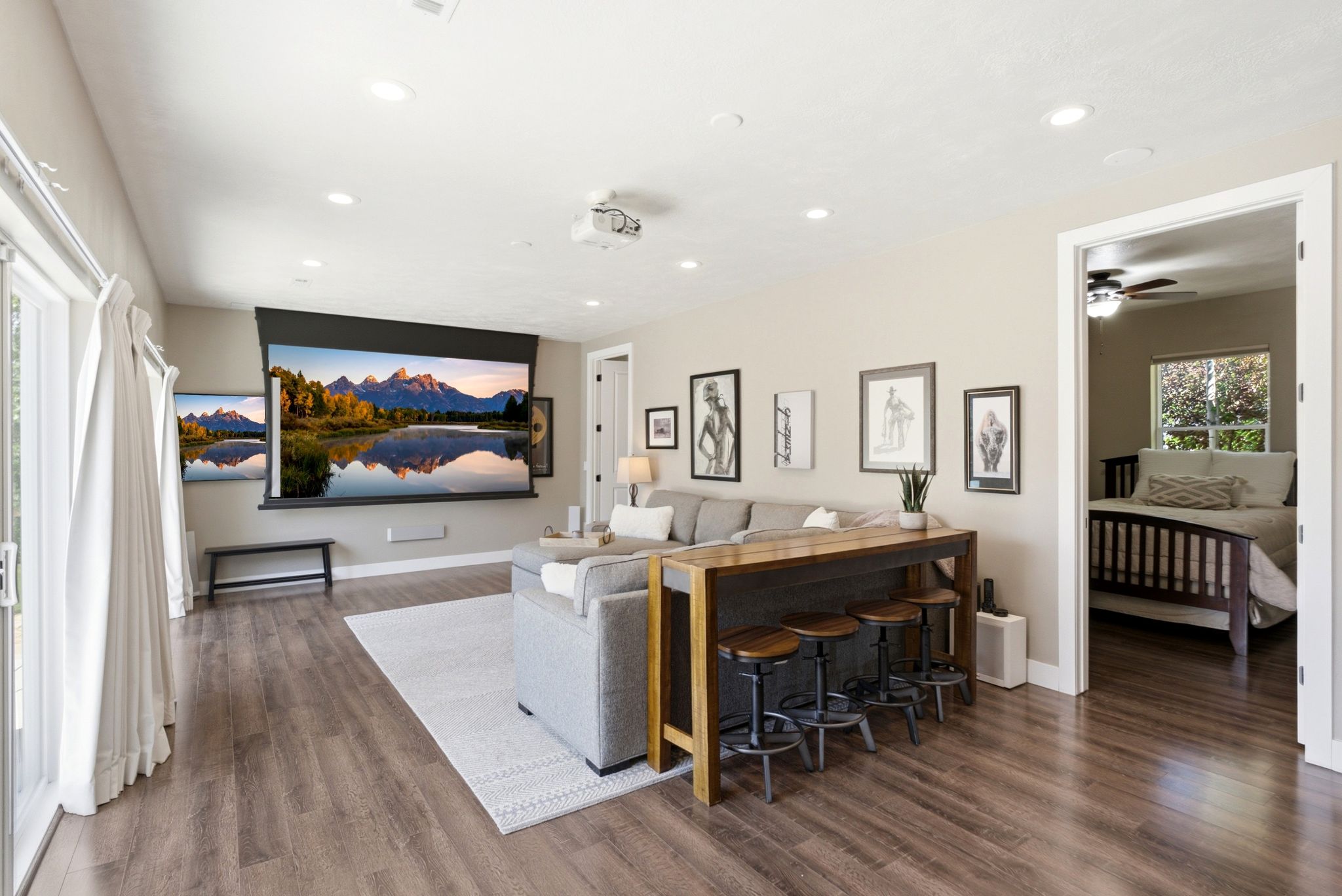 Spacious entertainment room featuring wood-finish flooring, recessed lighting, and a large projection screen