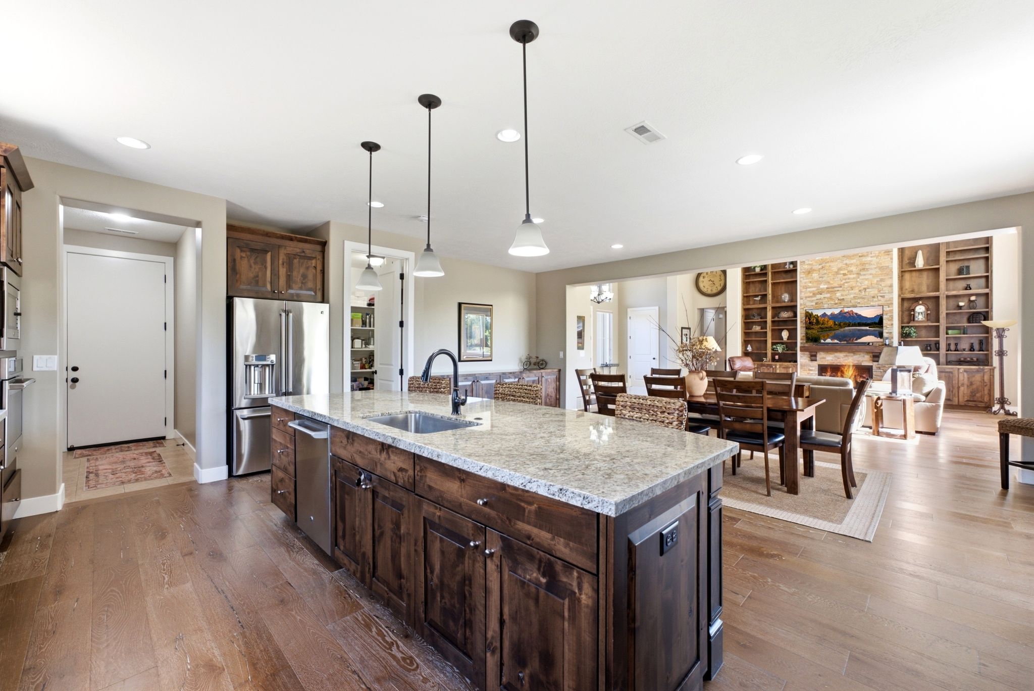 Open-concept kitchen featuring a large island with a light-colored countertop and dark wood-finish cabinetry