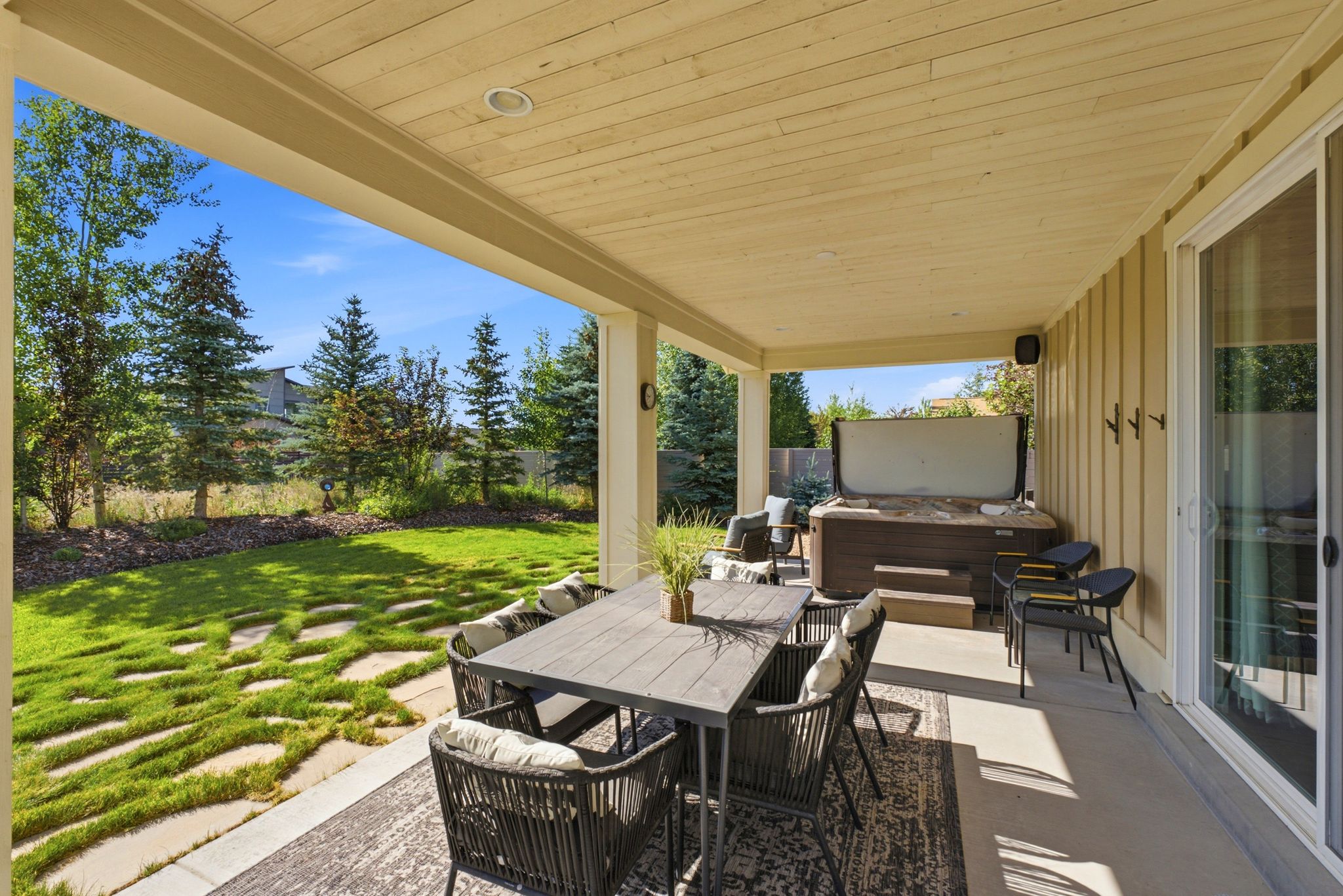 Covered patio featuring a built-in hot tub, concrete flooring, and a sliding glass door