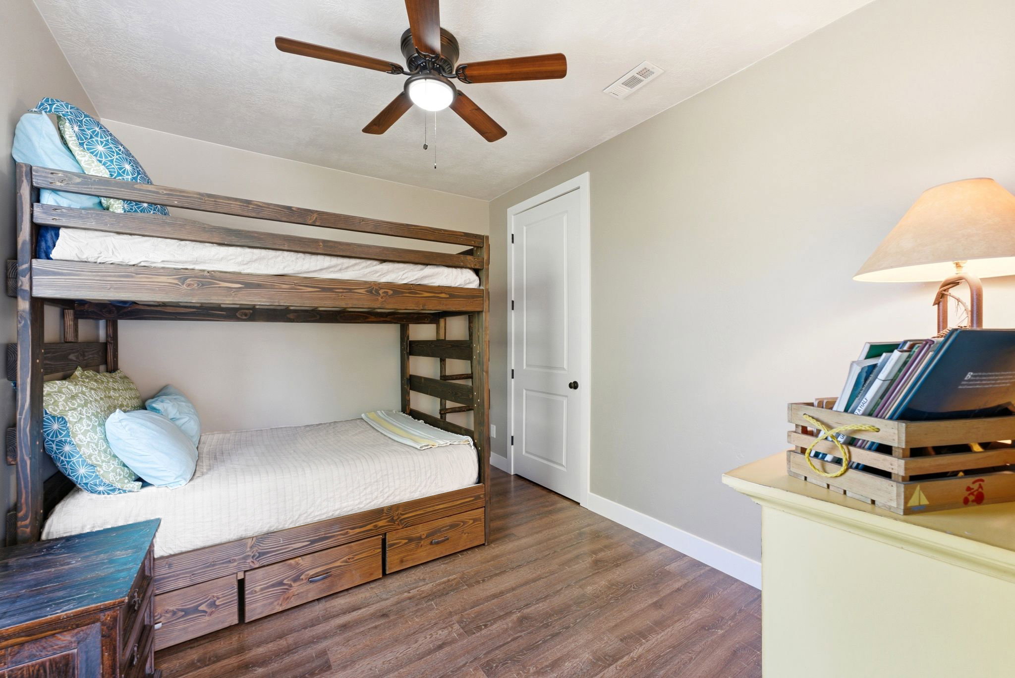Room featuring wood-finish flooring, a ceiling fan with integrated lighting, and a white interior door