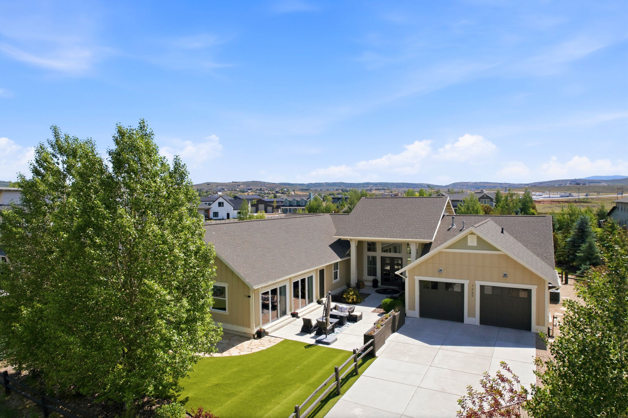 Expansive property featuring a two-car garage, concrete driveway, and a stone patio