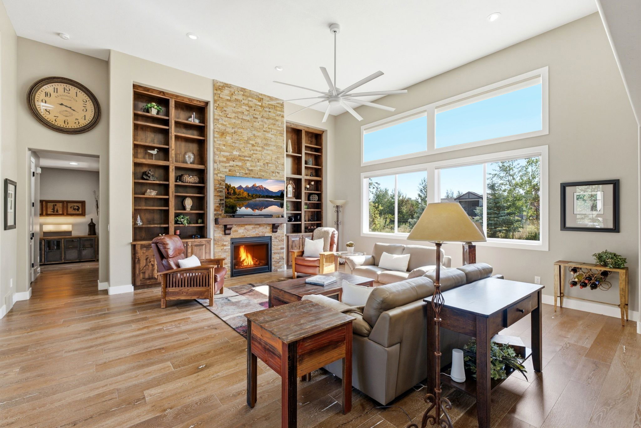 Spacious living area featuring a stone-faced fireplace, vaulted ceilings, and extensive wood-finish flooring