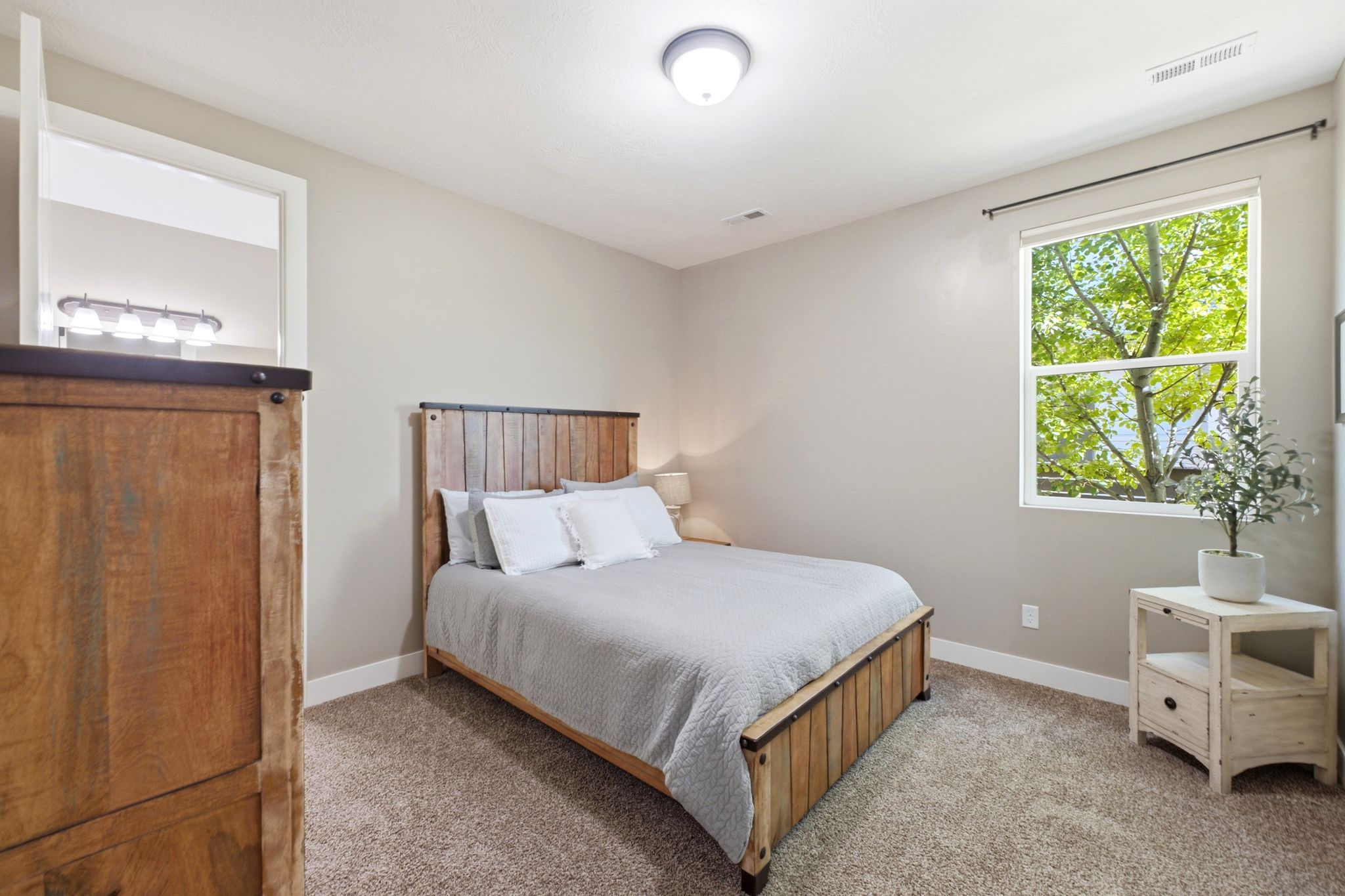 Carpeted bedroom featuring a large window, neutral wall paint, and a built-in light fixture