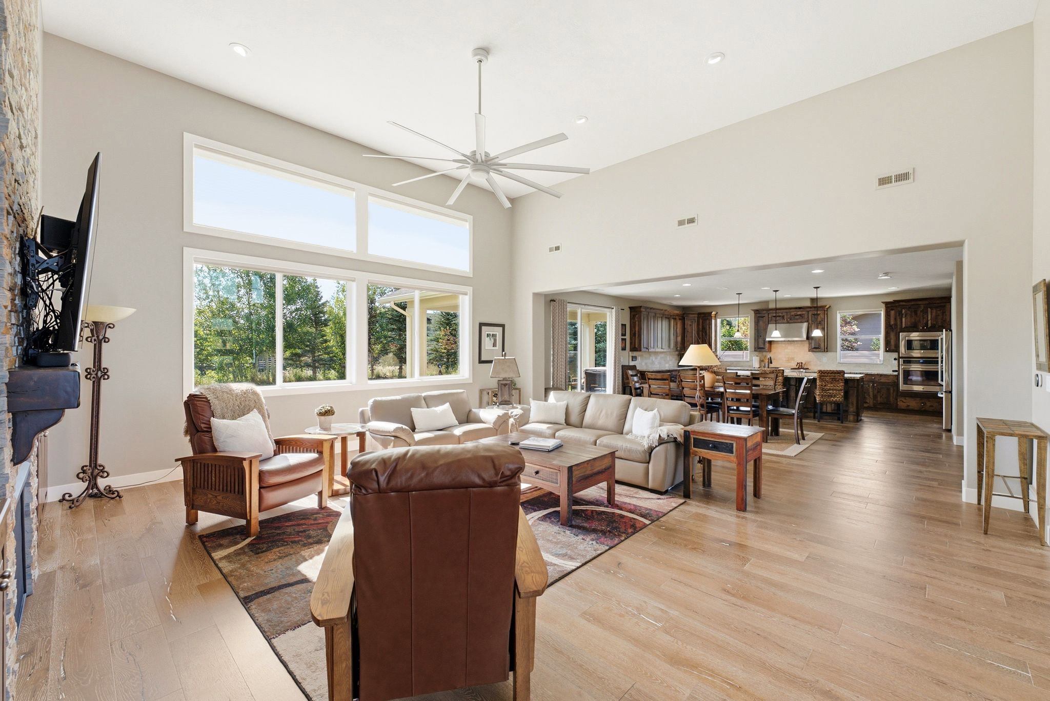 Expansive living room featuring soaring ceilings, abundant natural light from large windows, and light wood-finish flooring
