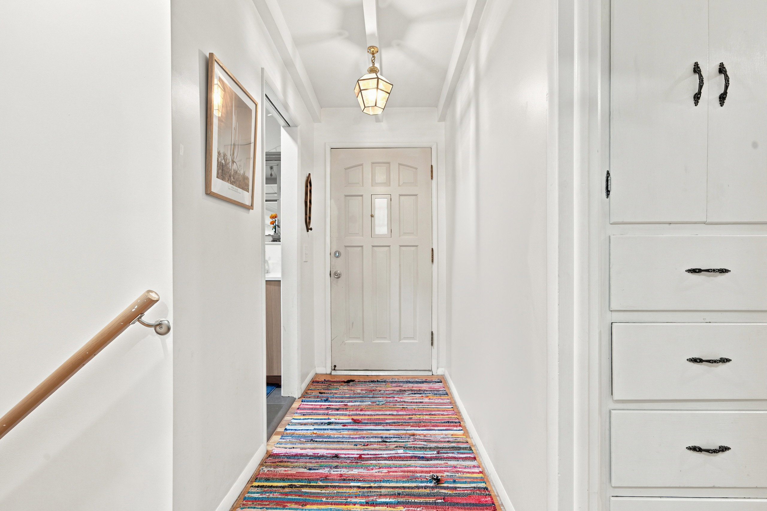 Entryway featuring a paneled door, built-in cabinetry, exposed beam ceiling, and a decorative ceiling light fixture