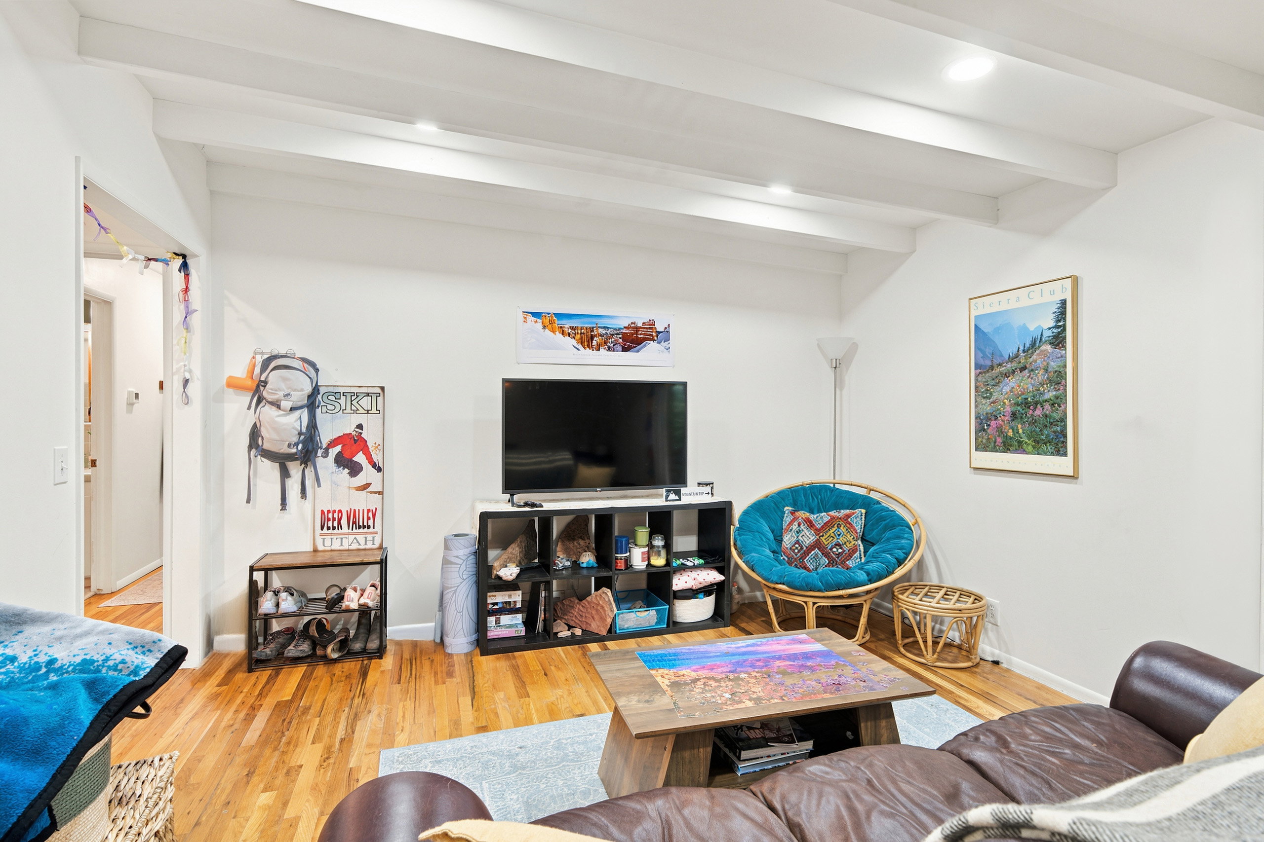 Living area featuring wood-finish flooring, exposed white ceiling beams, and recessed lighting