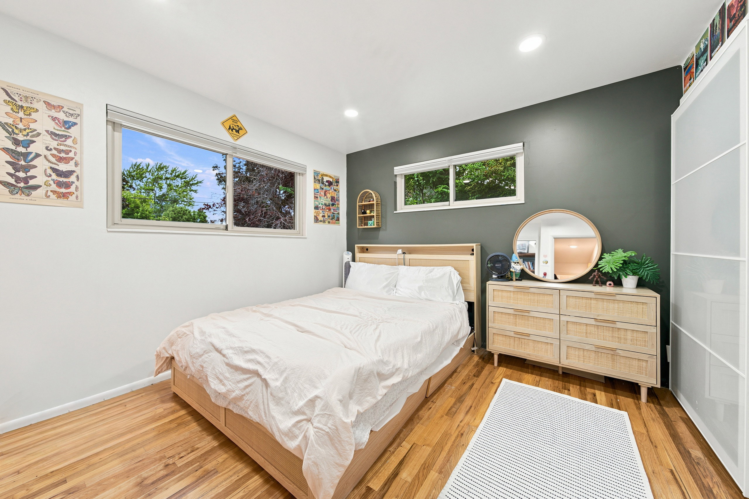 Hardwood flooring provides a warm foundation for this bedroom, featuring a contemporary accent wall and recessed lighting