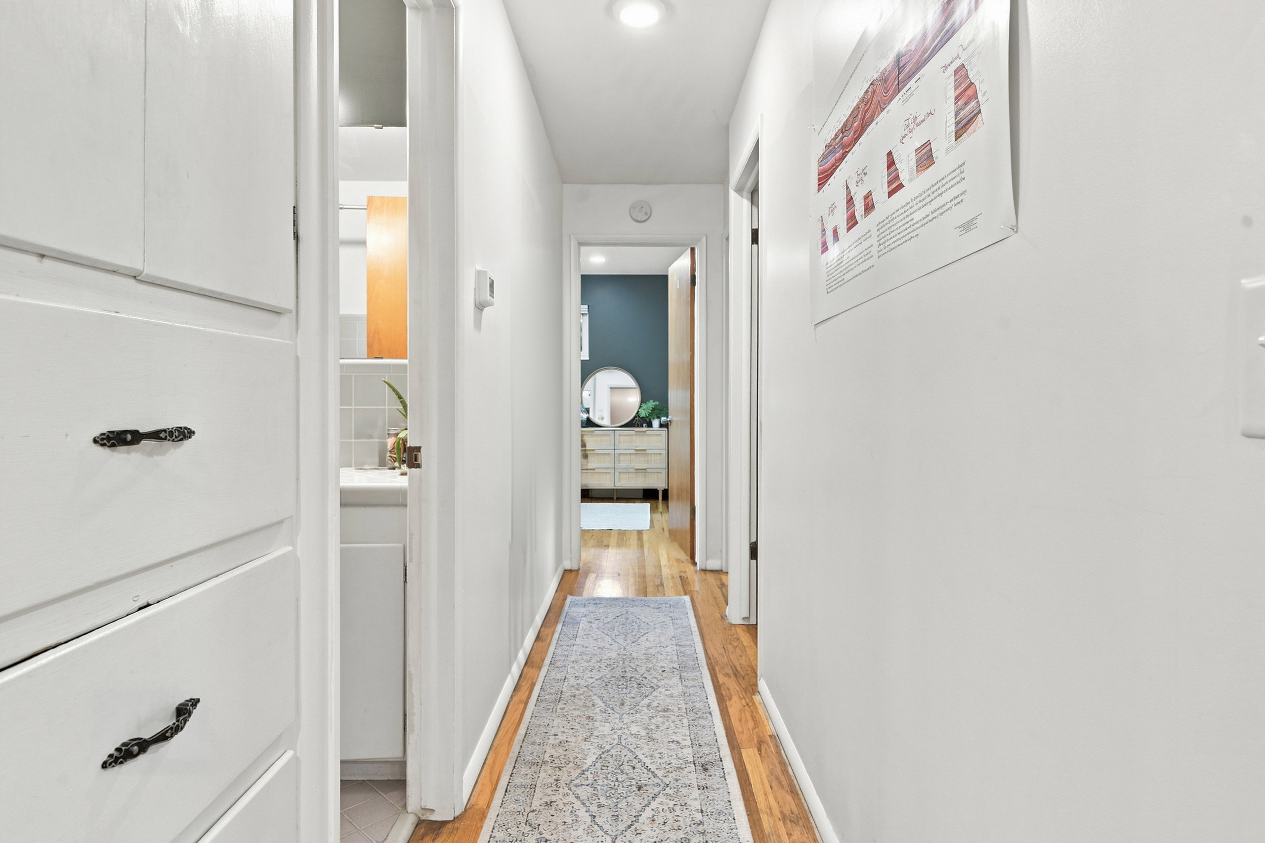 Hallway featuring built-in white cabinetry, hardwood flooring, and recessed lighting