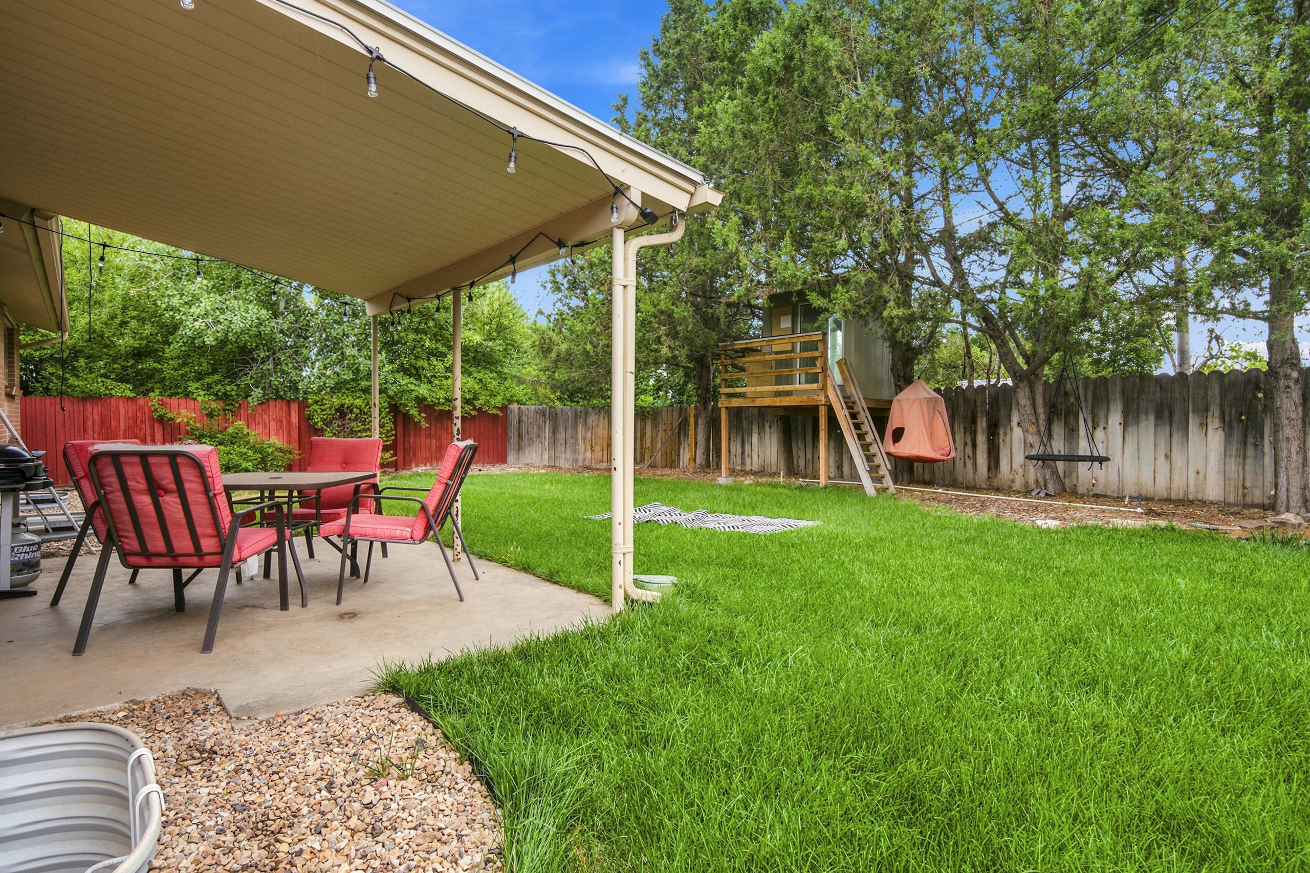 Expansive backyard featuring a covered patio, concrete surface, gravel accent, and a privacy fence